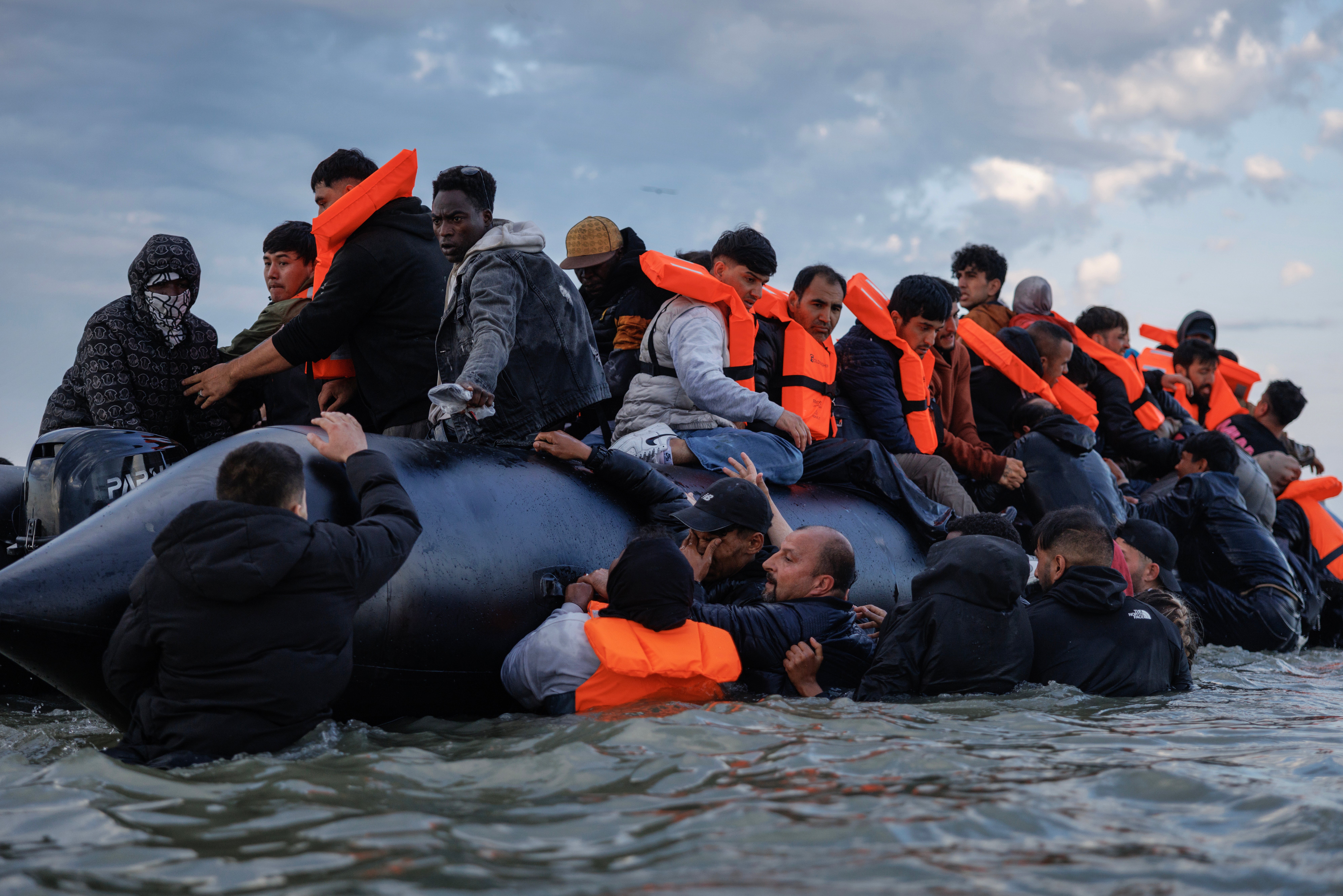 Migrant families clamber onto a small boat on August 12, 2025 in Gravelines, France.