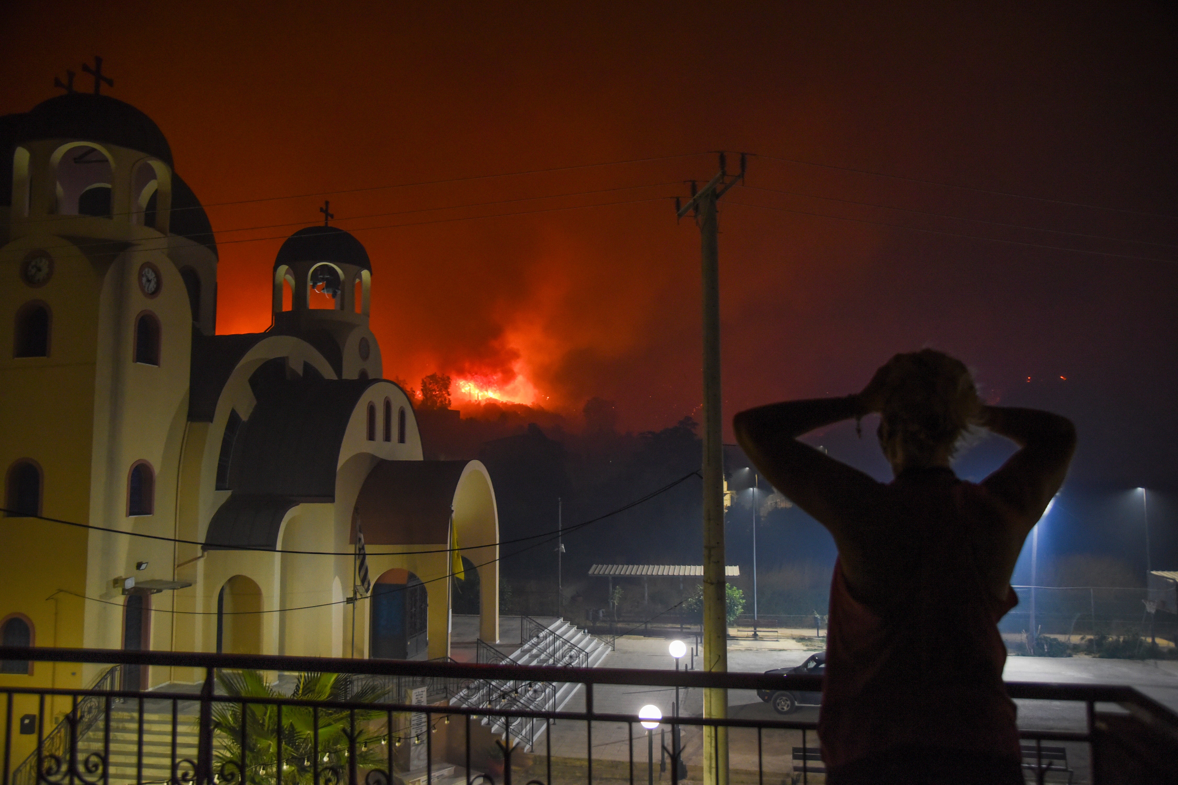 <p>A resident reacts as blazes burn a hill during a wildfire in the village of Tsoukalaiika near Patras city, western Greece</p>