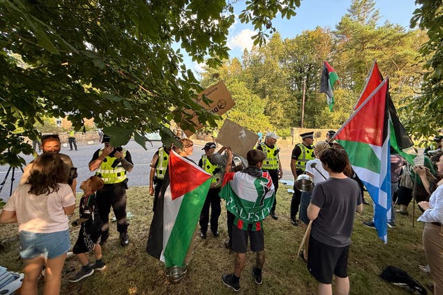 Police officers speak to protesters, some holding Palestinian flags, outside the Carnell Estate in Ayrshire (Craig Meighan/PA)