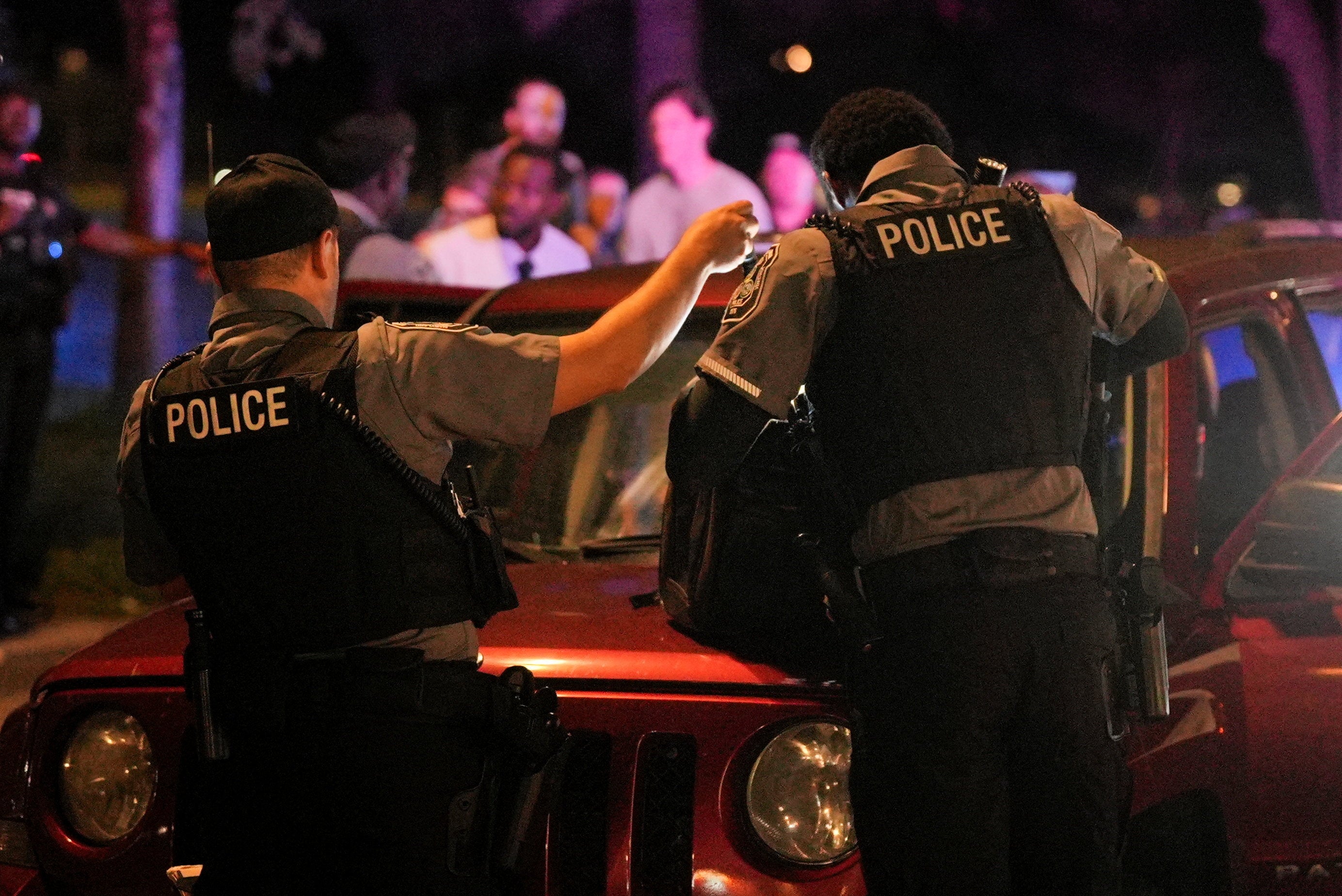 Police officers check the belongings of a person detained for a driver's license issue in Washington, D.C. Trump has flooded the streets of the nation’s capital with federal officers.