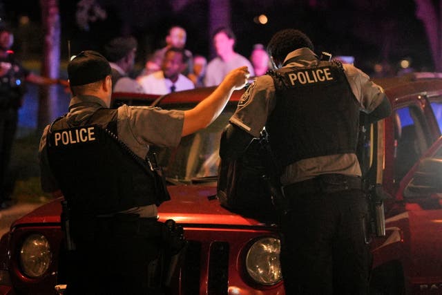 <p>Police officers check the belongings of a person detained for a driver's license issue in Washington, D.C. Trump has flooded the streets of the nation’s capital with federal officers.</p>