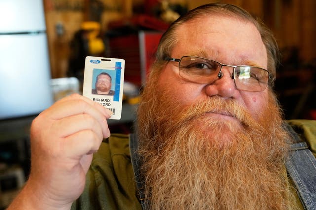 <p>Richard Guilford poses for a portrait with an ID card from his recently recovered wallet that he lost 11 years ago</p>