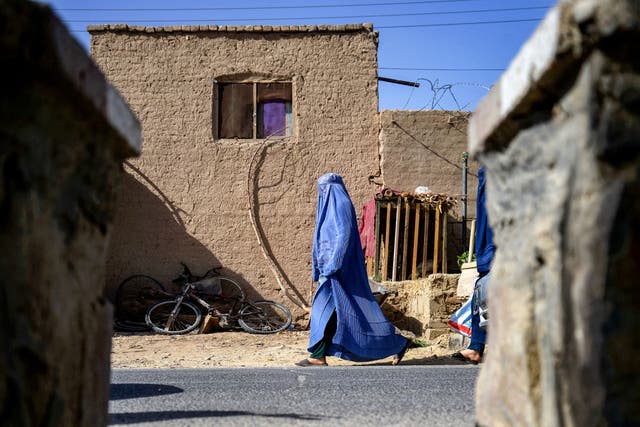 <p>An Afghan burqa-clad woman walks along a street in Kandahar</p>
