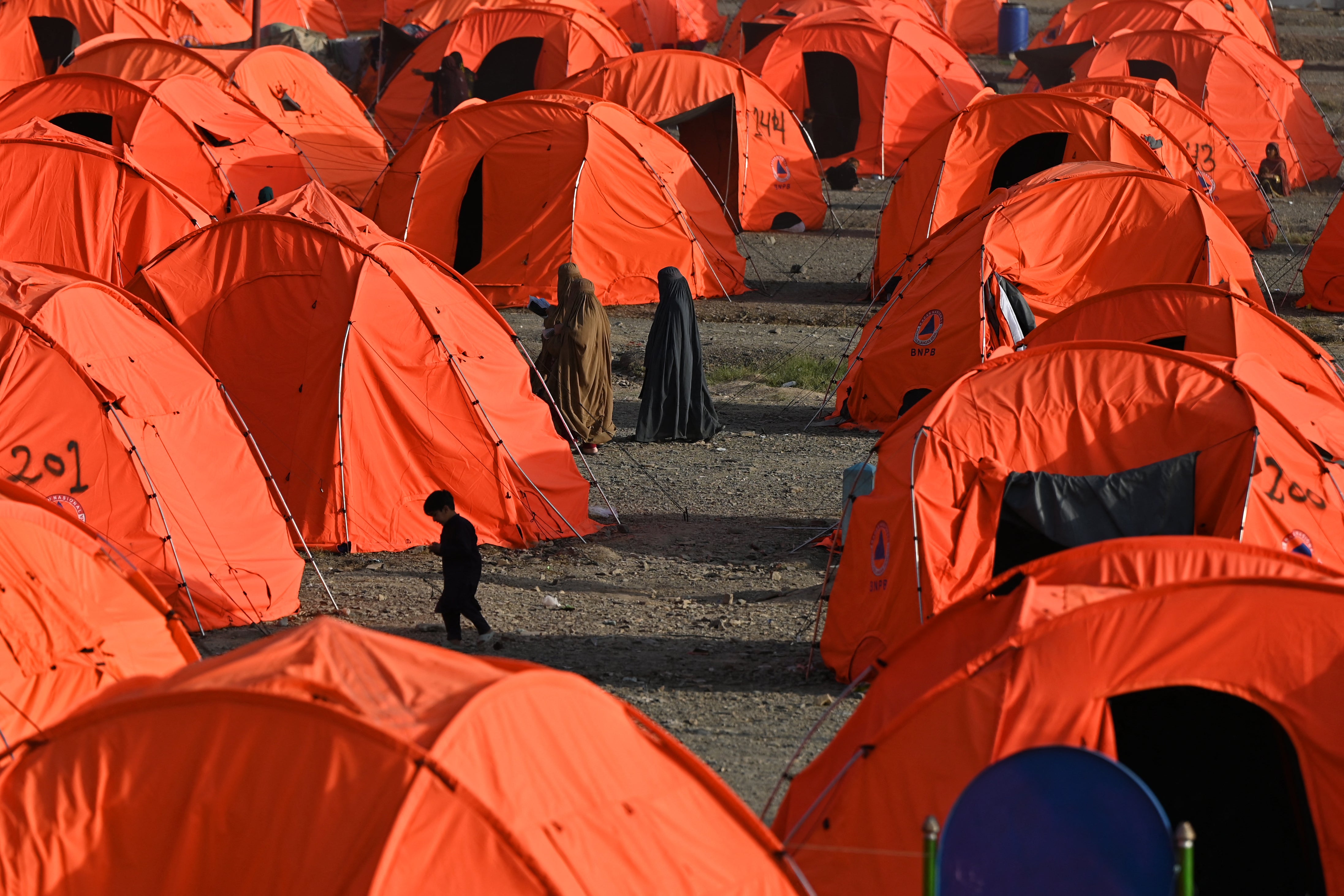 Afghan refugee women walk through tents after arriving from Pakistan at a makeshift camp in Nangarhar province