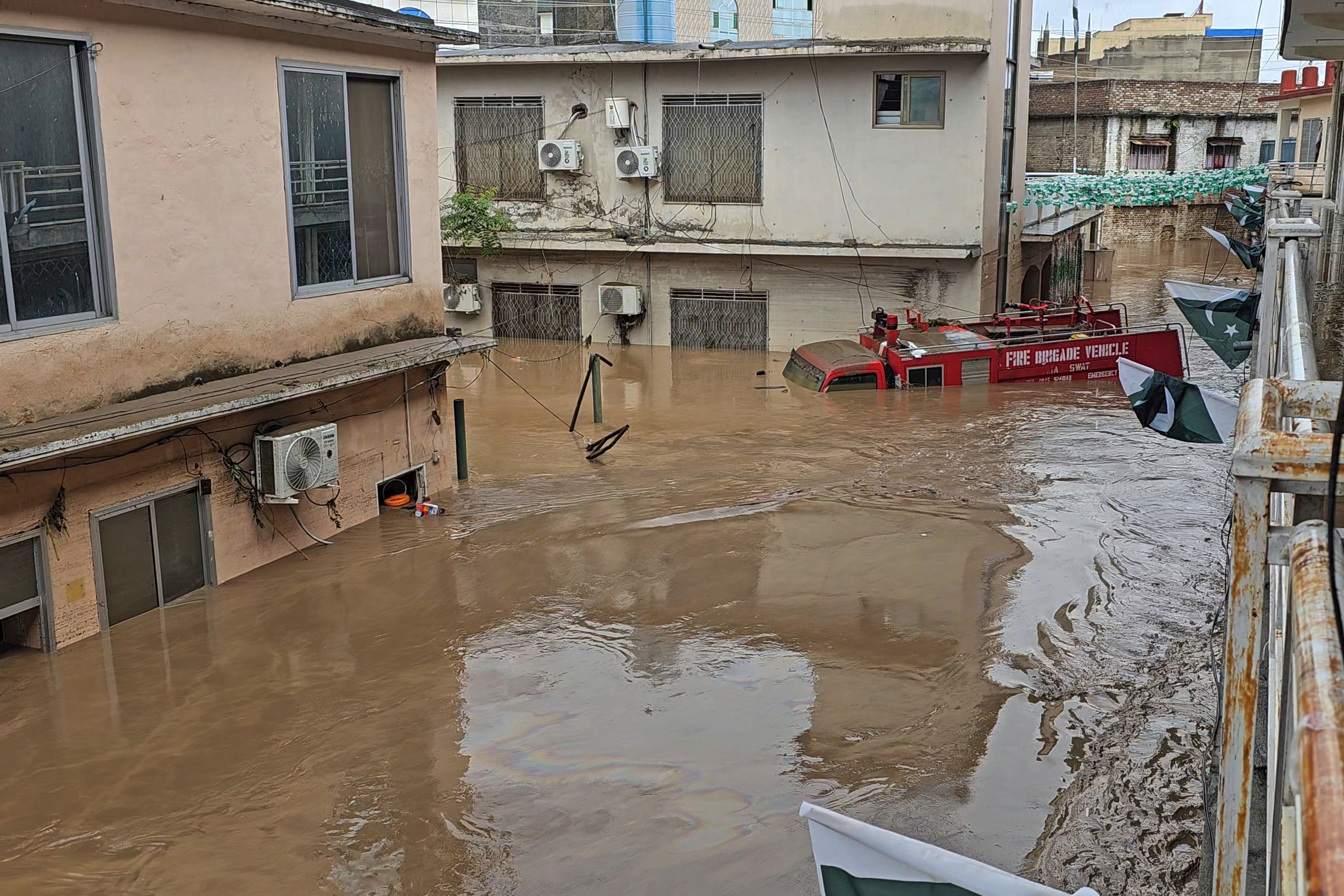 A firefighting department vehicle submerged in a floodwater following flash flooding due to heavy rains in the neighbourhood of Mingora, the main town of Swat Valley, northwestern Pakistan, Friday