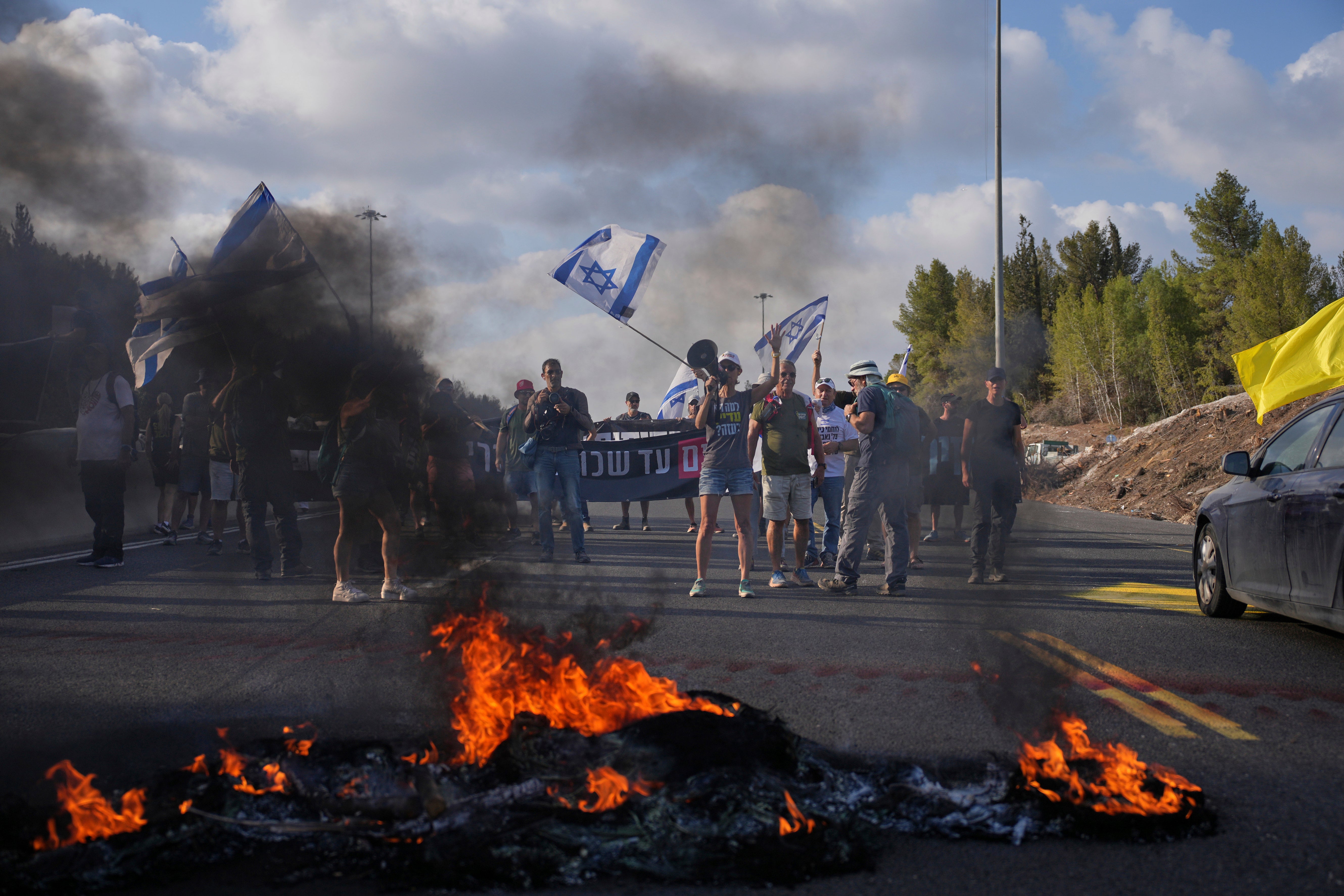 Demonstrators block a road during a protest demanding the immediate release of hostages held by Hamas and calling for the Israeli government to reverse its decision to take over Gaza City and other areas in the Gaza Strip, near Jerusalem, Israel, Sunday, Aug. 17, 2025. (AP Photo/Ohad Zwigenberg)