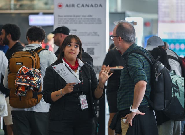 <p>An Air Canada agent, left, talks with a man as Air Canada flight attendants strike at Montreal-Pierre Elliott Trudeau International Airport in Montreal, Saturday, Aug. 16, 2025</p>
