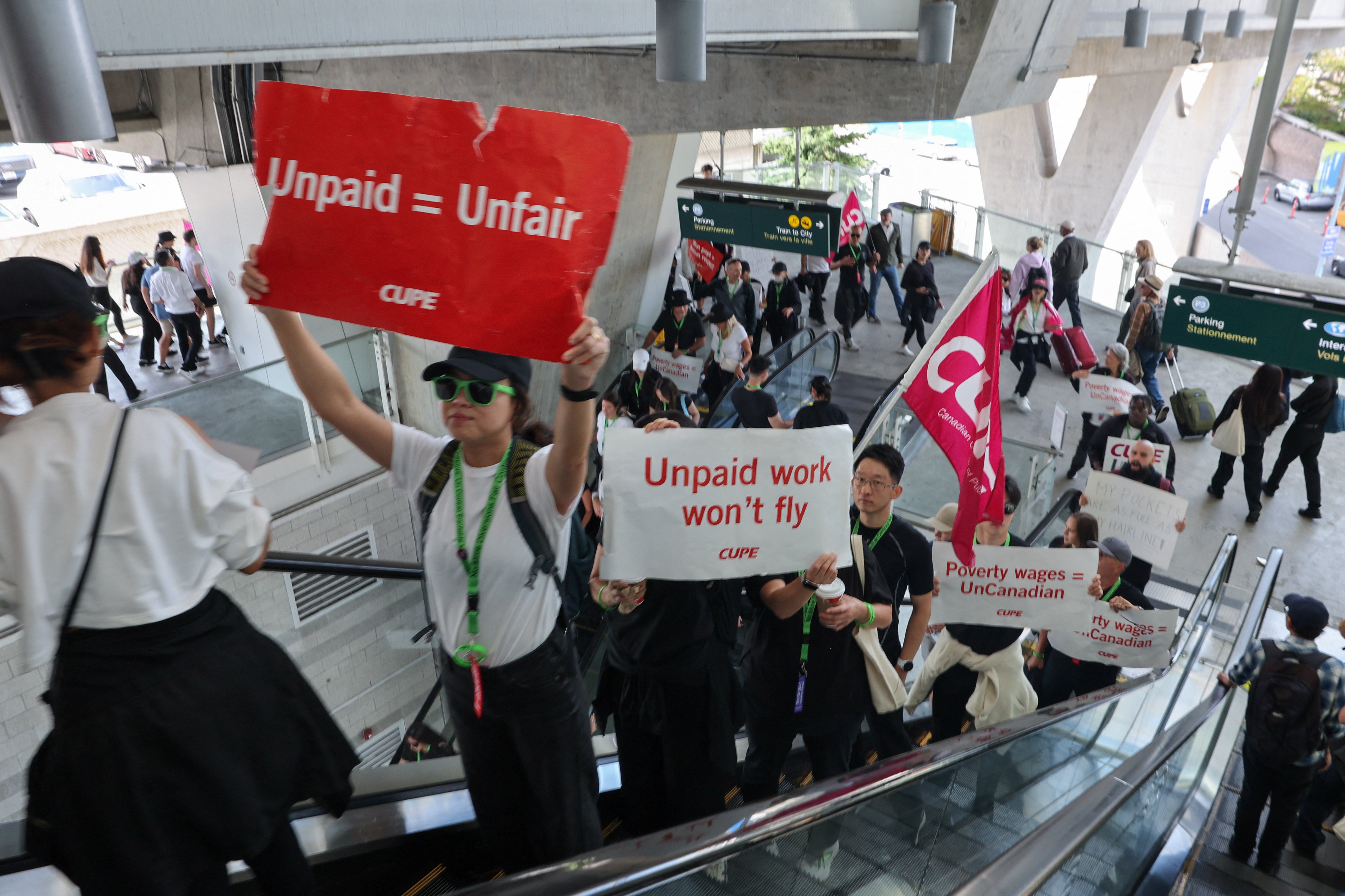 <p>Demonstrators display placards while riding an escalator as Air Canada flight attendants said they will remain on strike and challenge a return-to-work order they called unconstitutional, defying a government decision to force them back to their duties, at Vancouver International Airport in Richmond, British Columbia, Canada, August 17</p>