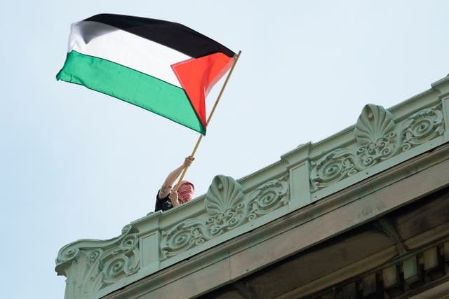 <p>A student protester waves a Palestinian flag above Hamilton Hall on the campus of Columbia University, on April 30, 2024 in New York City</p>