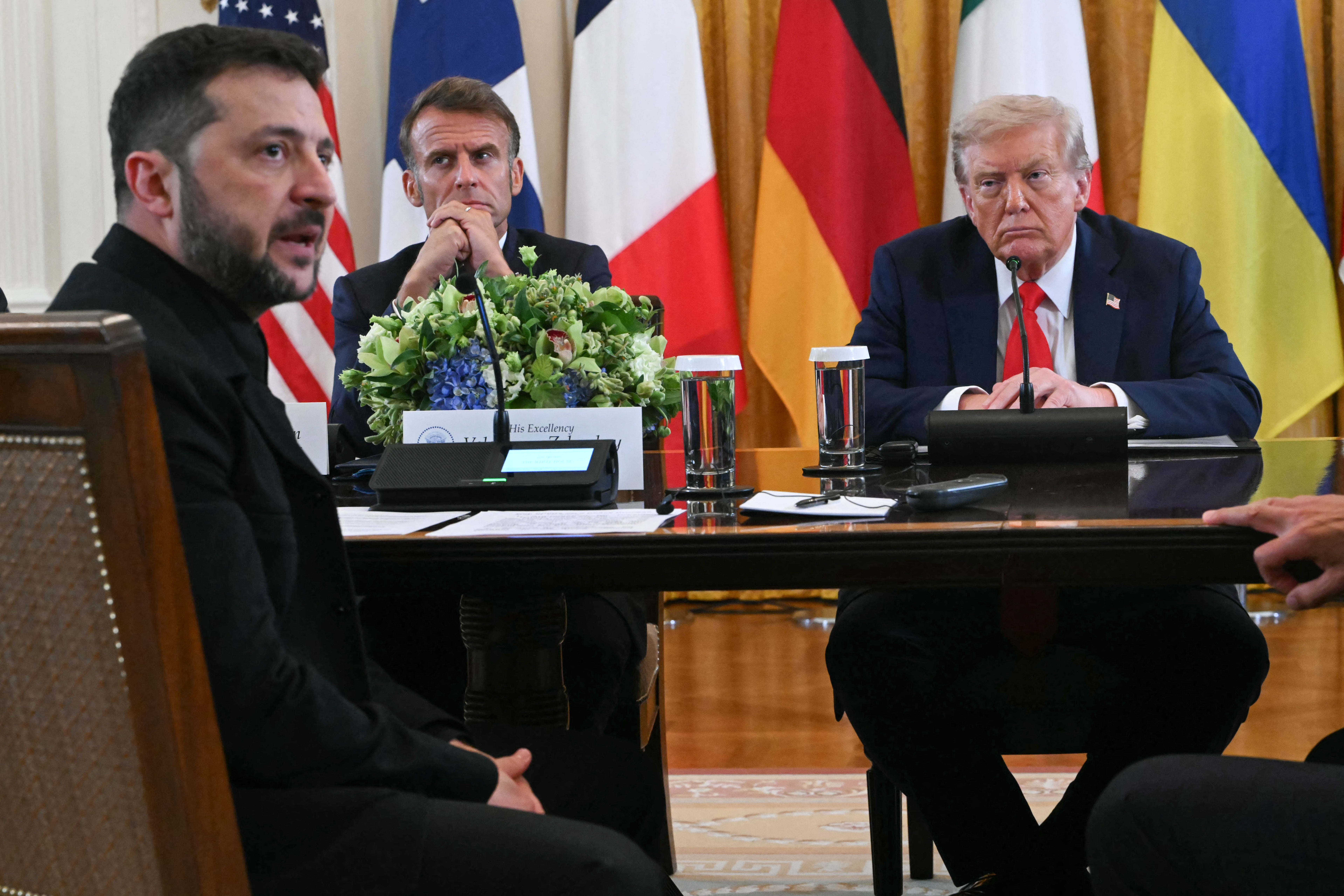 Ukrainian President Volodymyr Zelensky speaks as French President Emmanuel Macron and President Donald Trump listen during the gathering