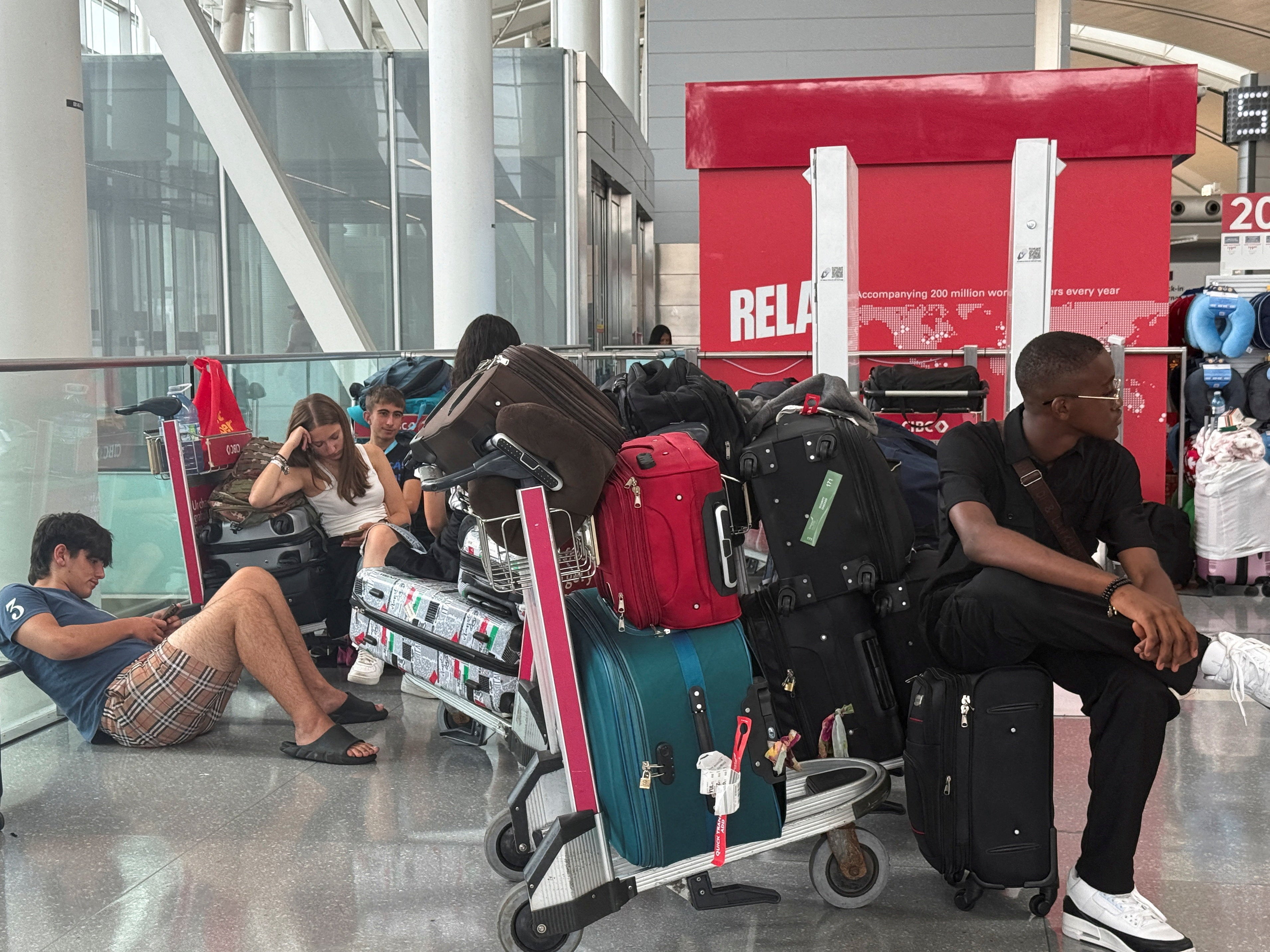 People sit with their luggage, as Air Canada flight attendants said they will remain on strike