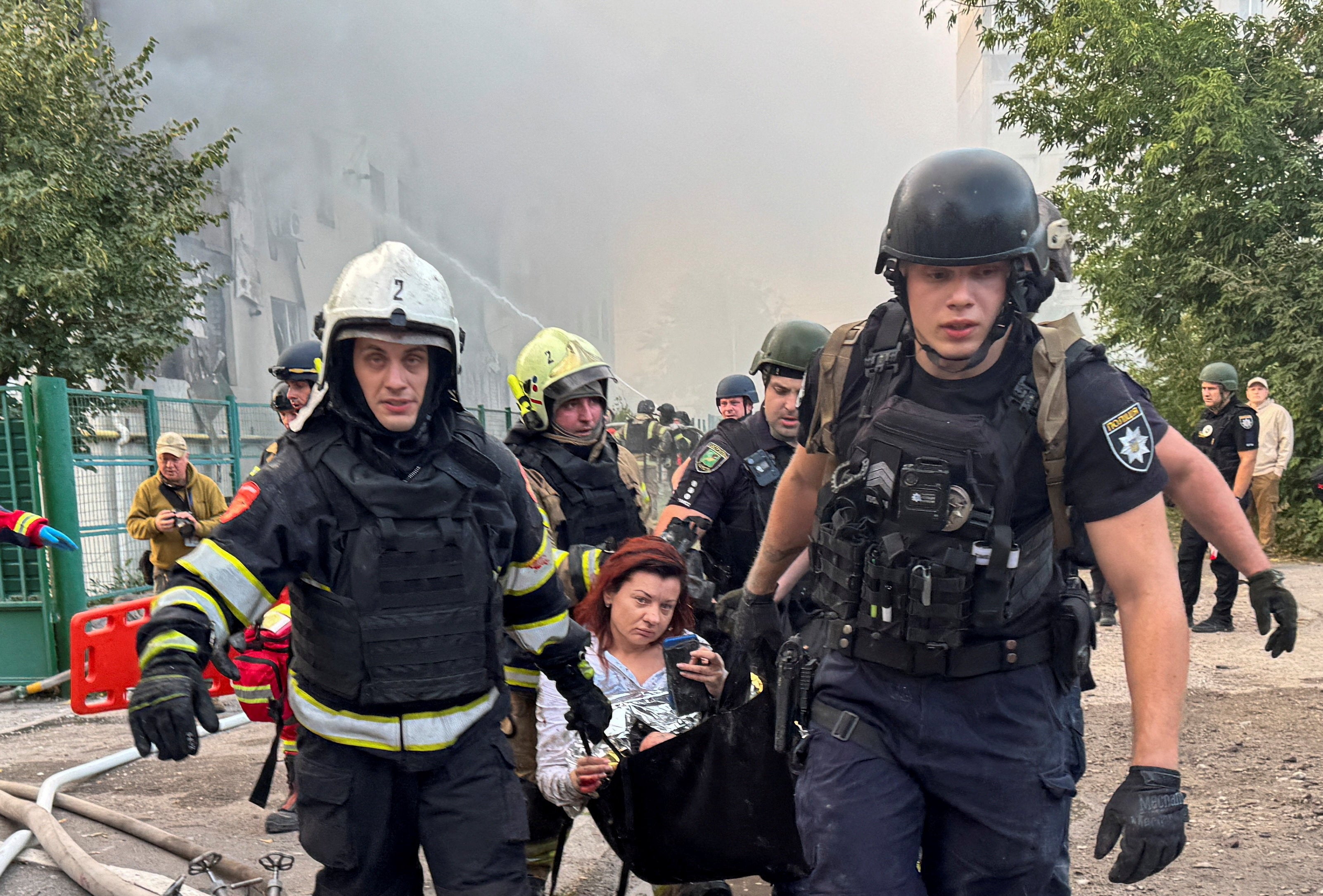 Emergency employees carry a woman rescued from debris at the site of an apartment building