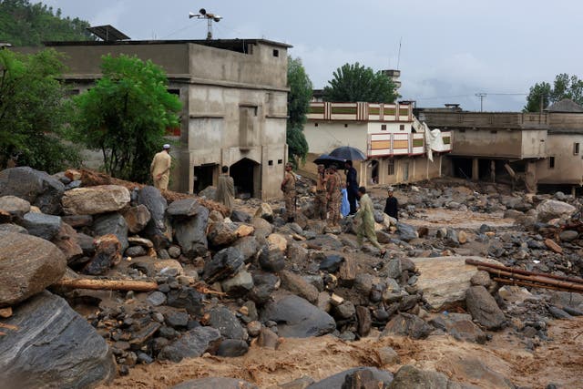 <p>Army soldiers survey damage at an area as rain water flowing from mountains crosses a damaged area, following a storm that caused heavy rains and flooding in Bayshonai Kalay, in Buner district</p>