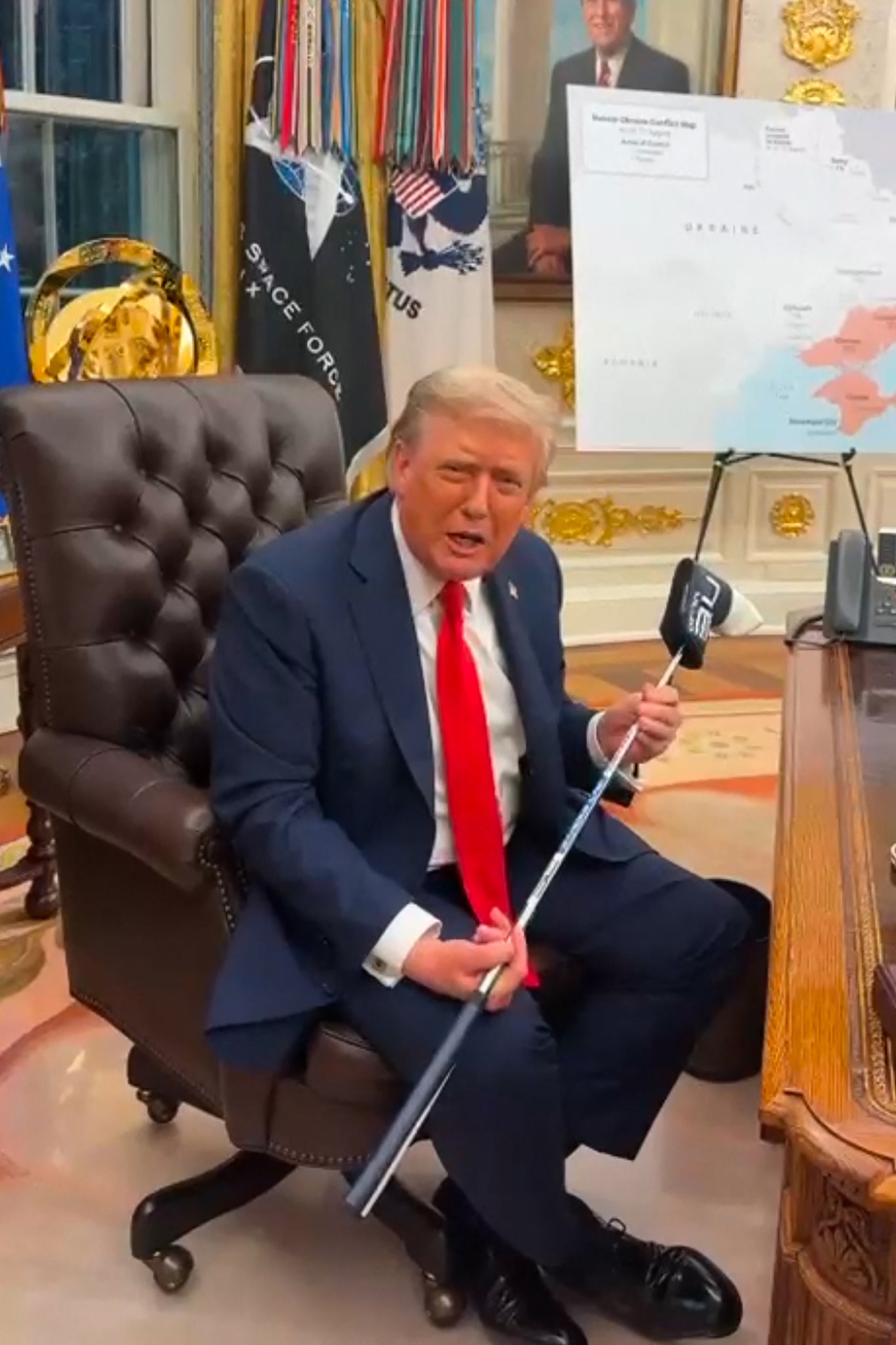 President Donald Trump holds a golf club gifted to him by Ukrainian President Volodymyr Zelensky