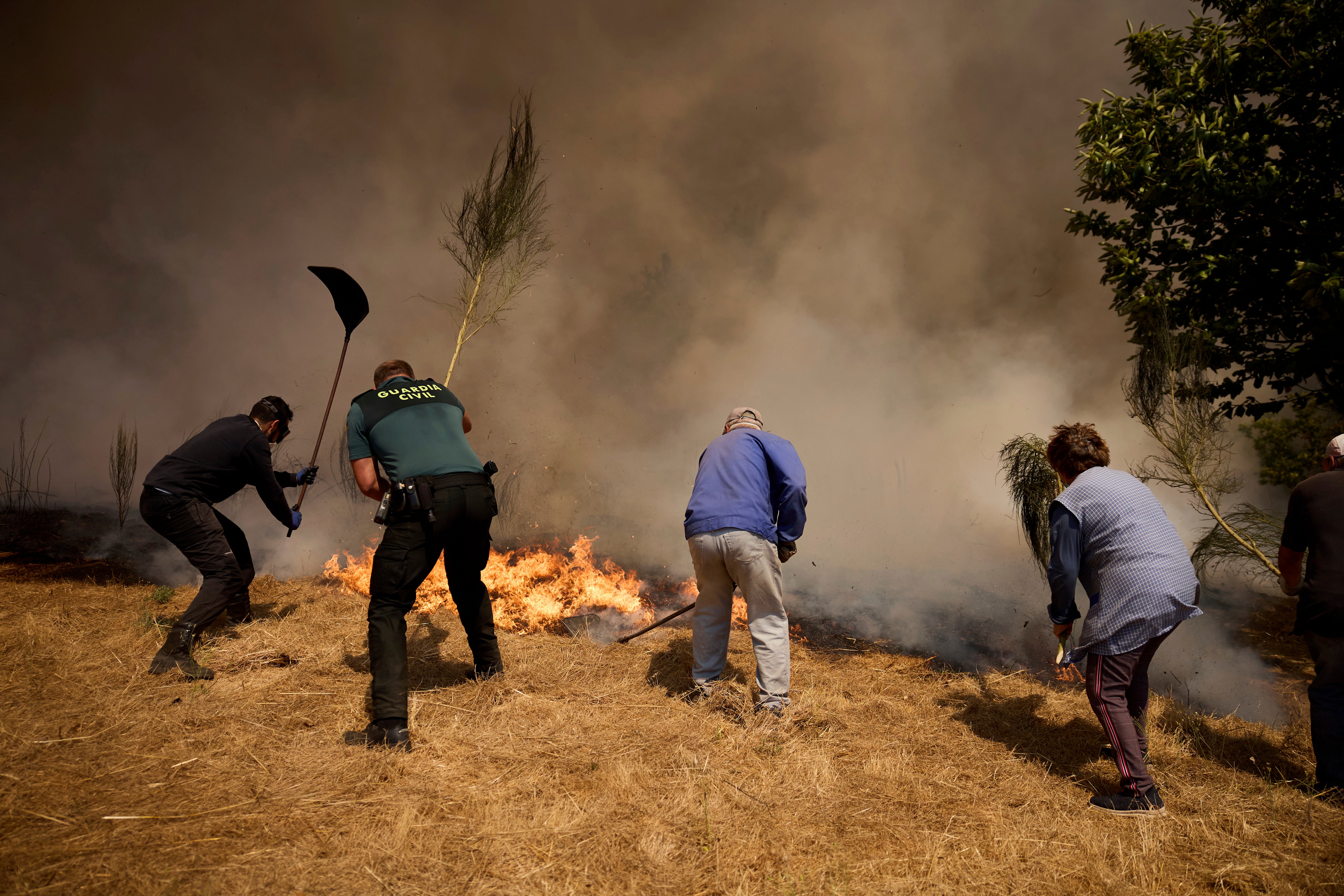 Residents battle a fire advancing toward Rebordondo village, near Ourense, in northwestern Spain, on Monday