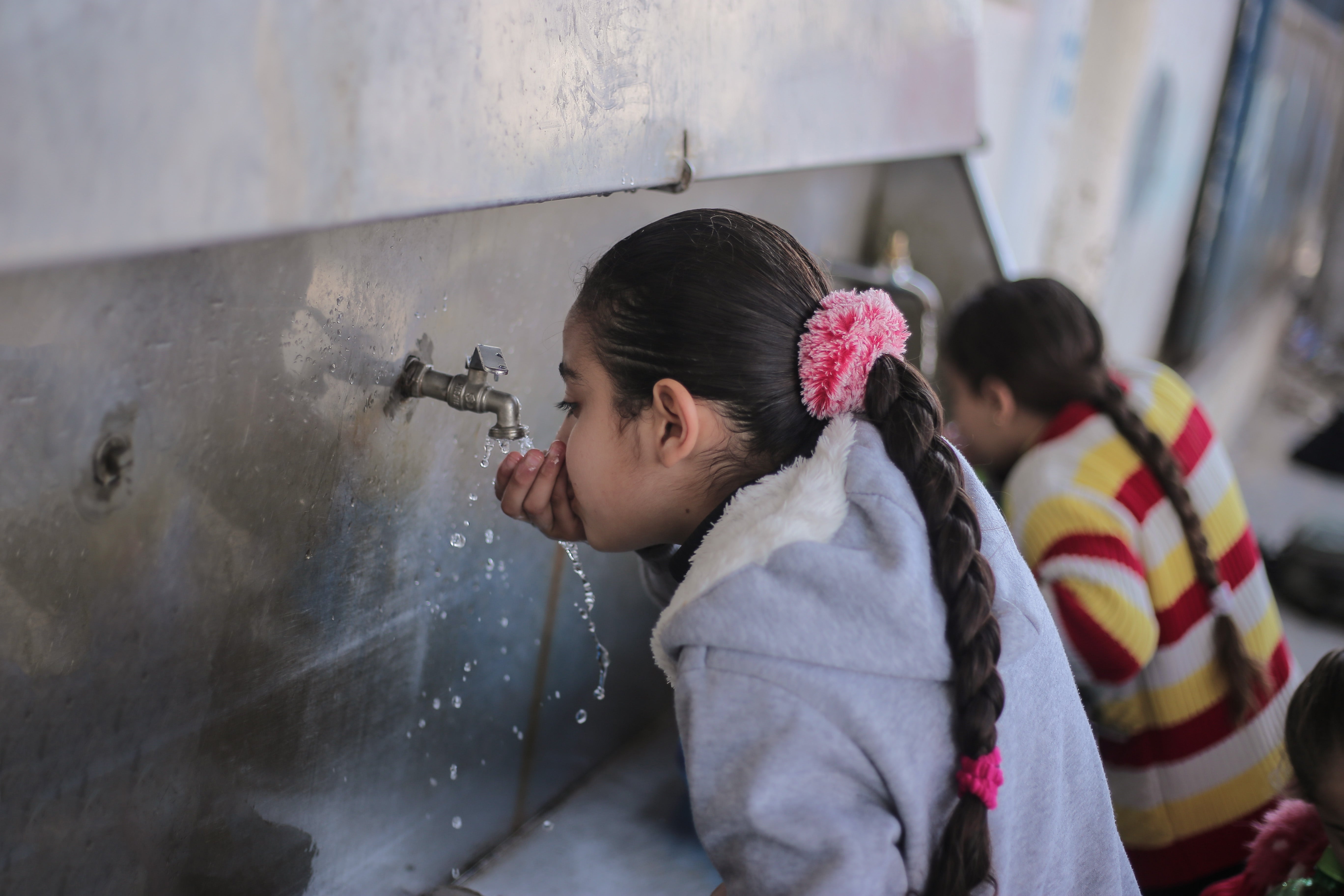 Young girls drink from communal taps