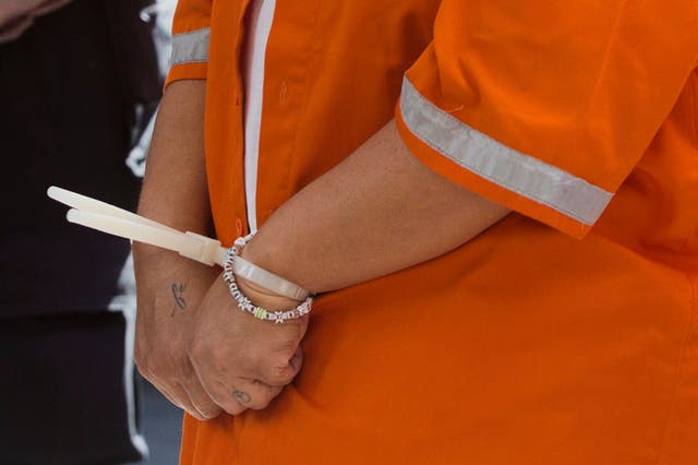 <p>A Peruvian national identified only as NS who was arrested on accusation of smuggling cocaine into the resort island of Bali, stands handcuffed as she is presented to the media during a press conference</p>