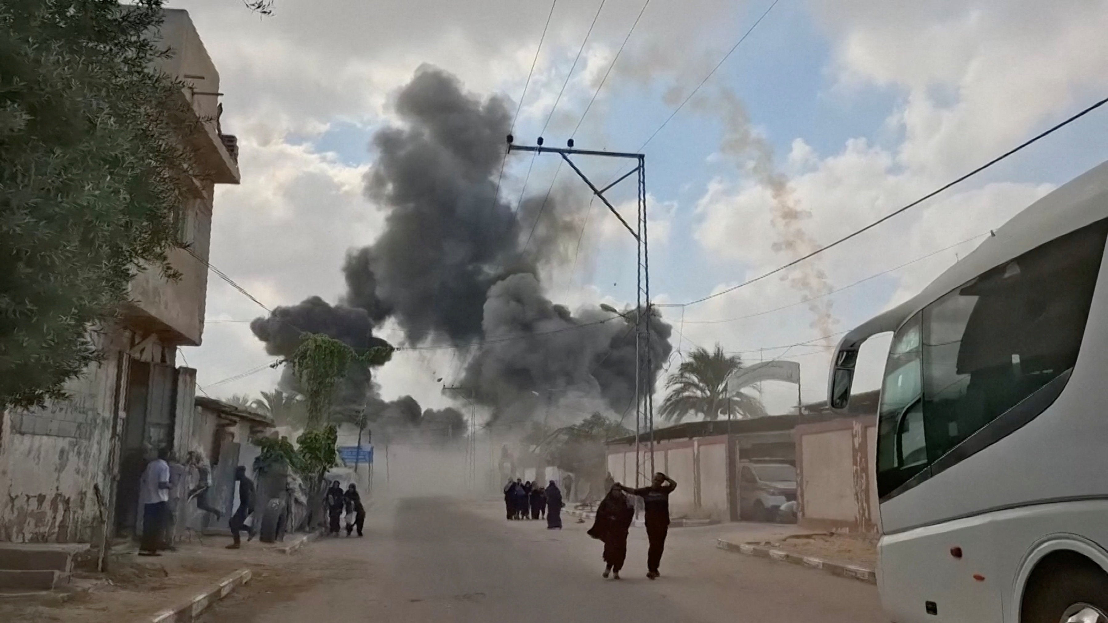 People run as plumes of smoke rise following an Israeli airstrike, amid the ongoing conflict between Israel and Hamas, in Deir al-Balah, Gaza Strip