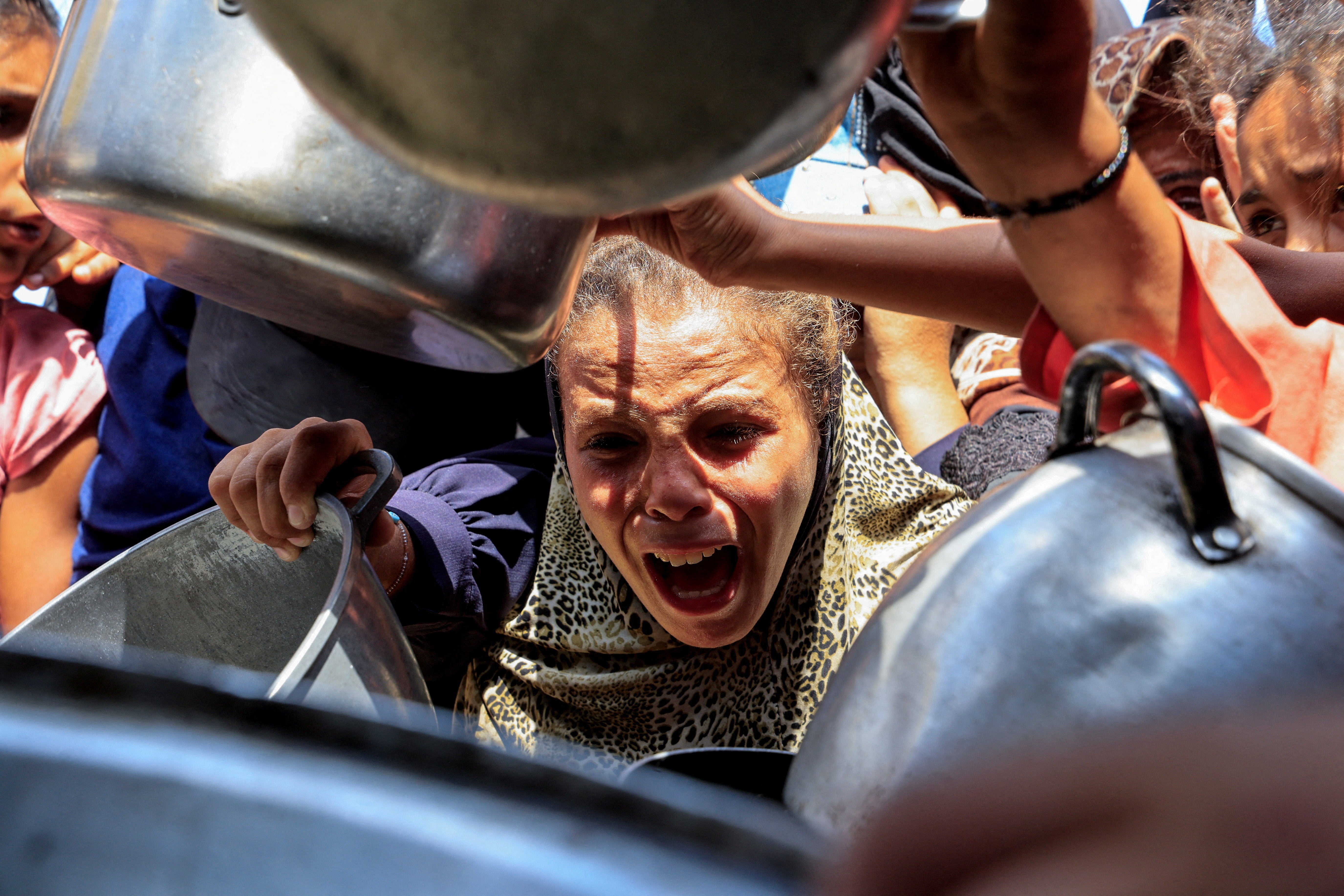 Palestinians wait to receive food from a charity kitchen, in Khan Younis
