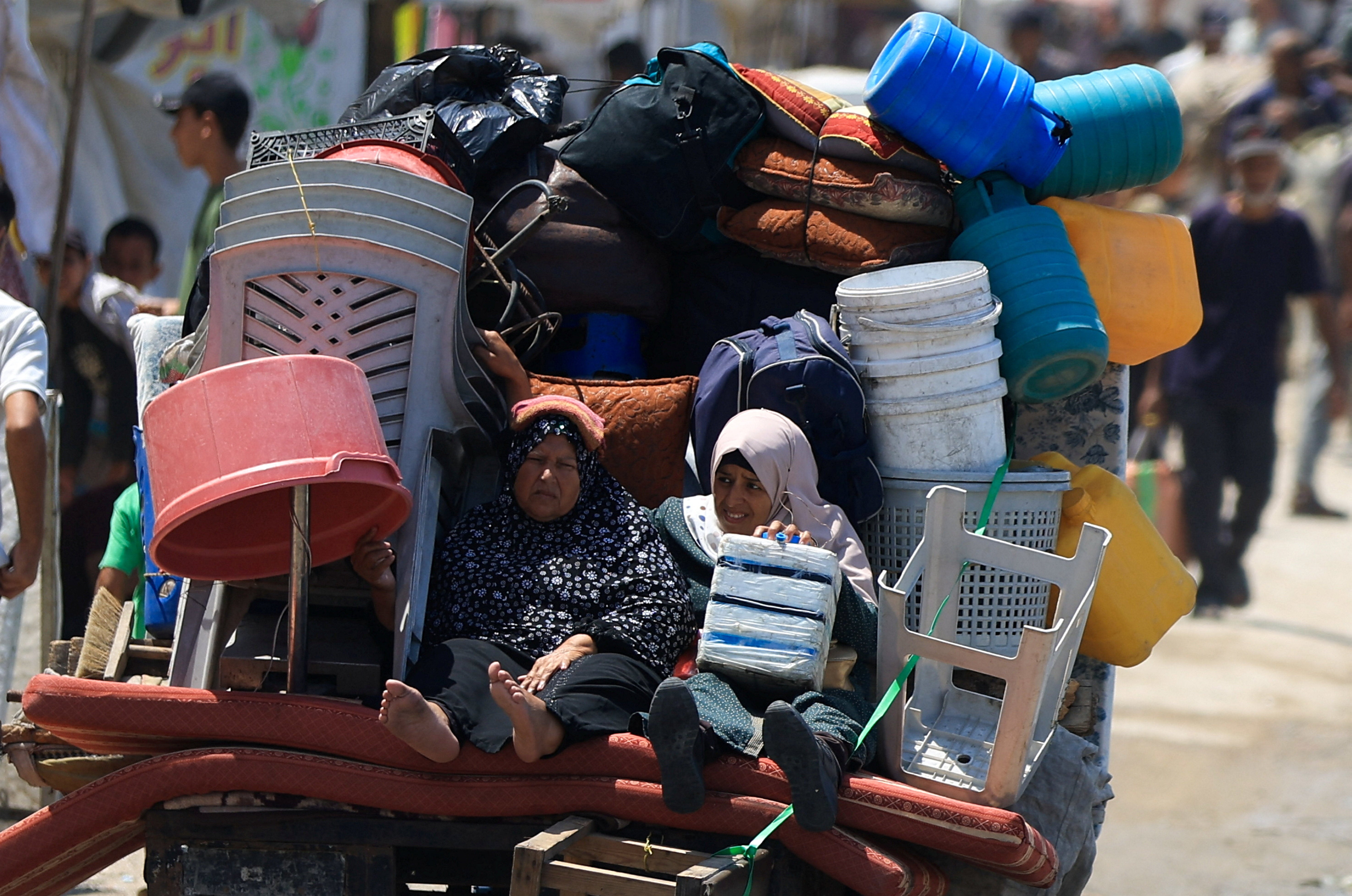 Displaced Palestinian women fleeing northern Gaza ride with their belongings as they head south, amid an Israeli military operation, in Gaza City