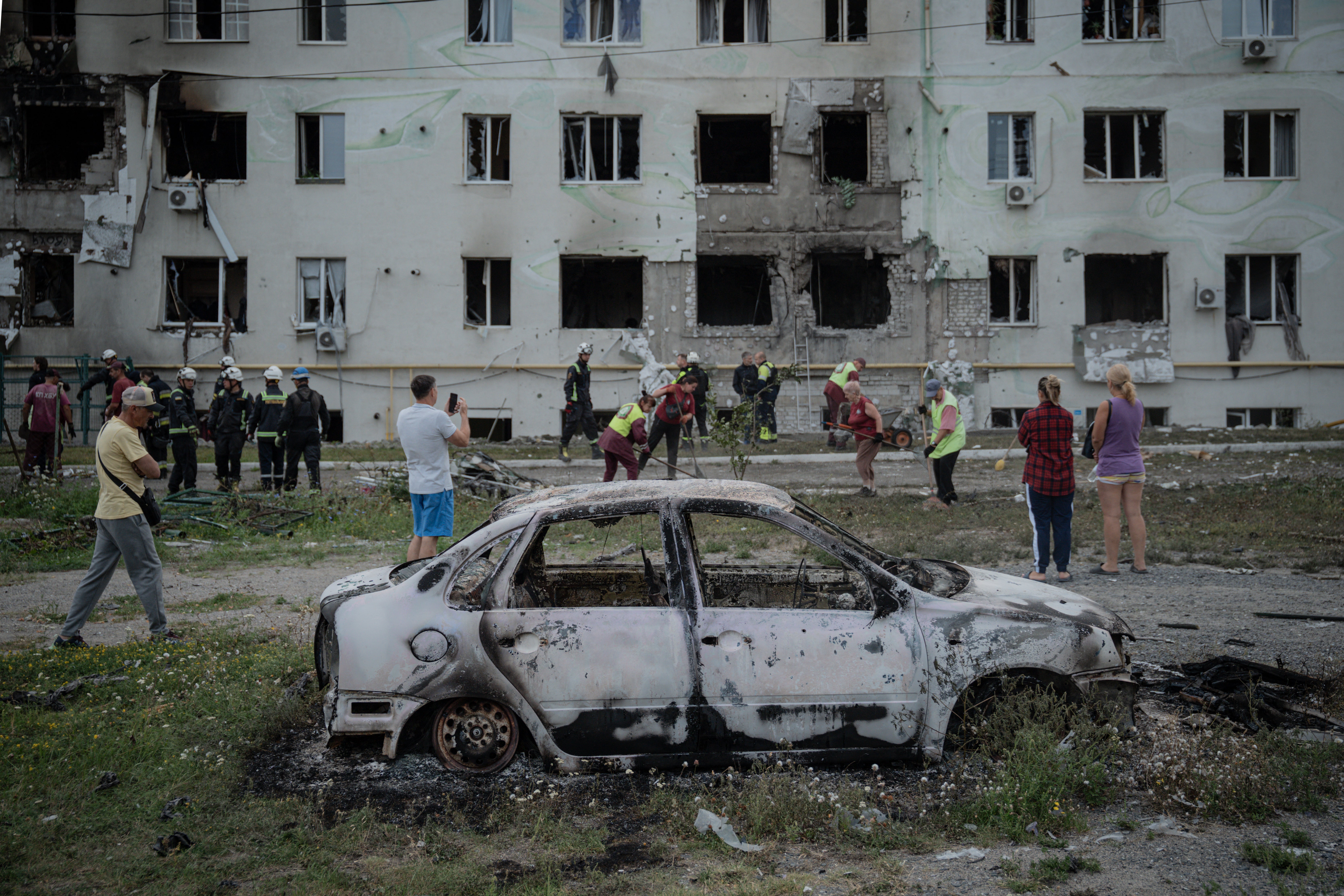 Ukrainian rescuers, city workers and local residents gather in front of a destroyed residential building after an air attack in Kharkiv