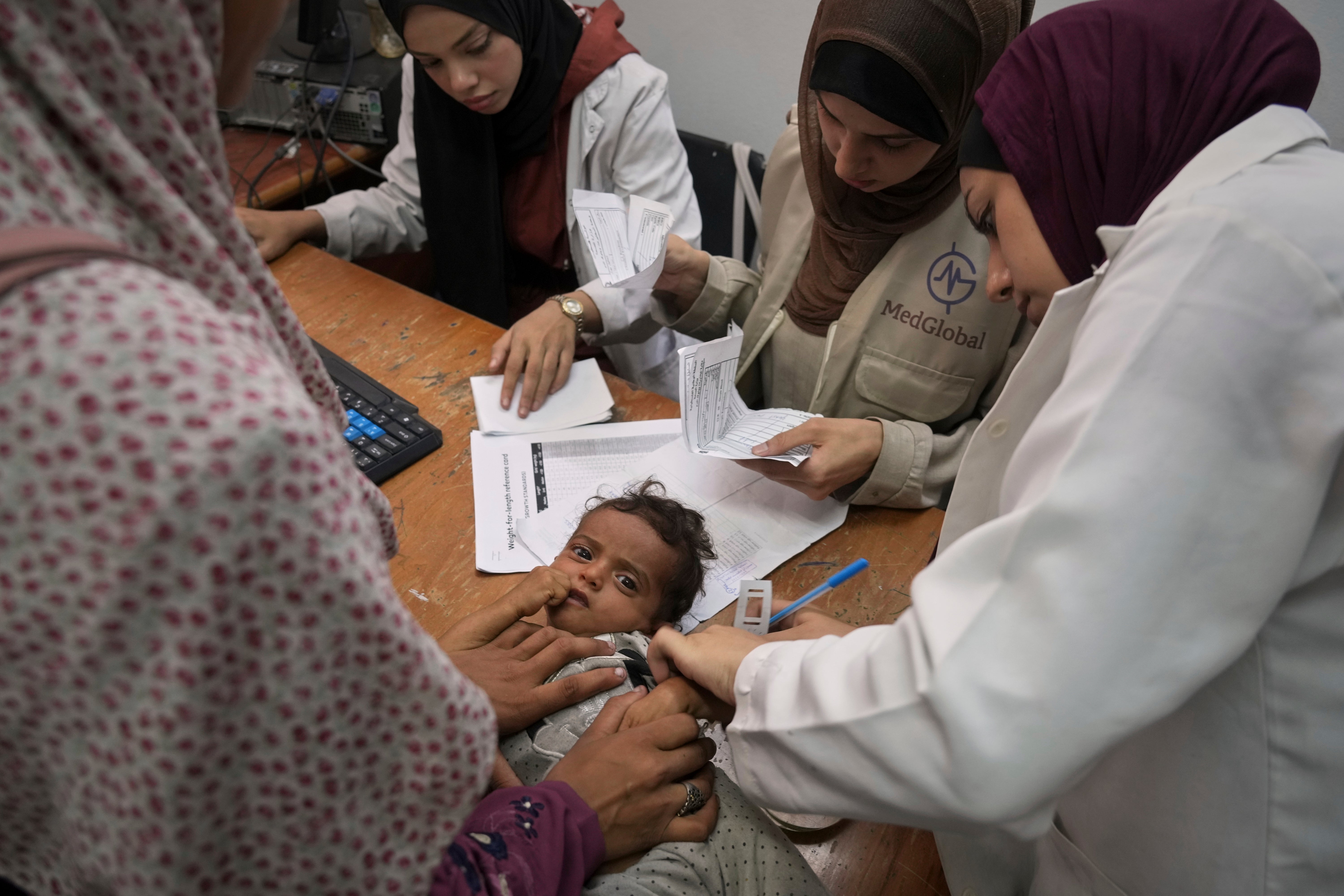 A doctor in Gaza City measures a child’s arm to check for signs of malnutrition