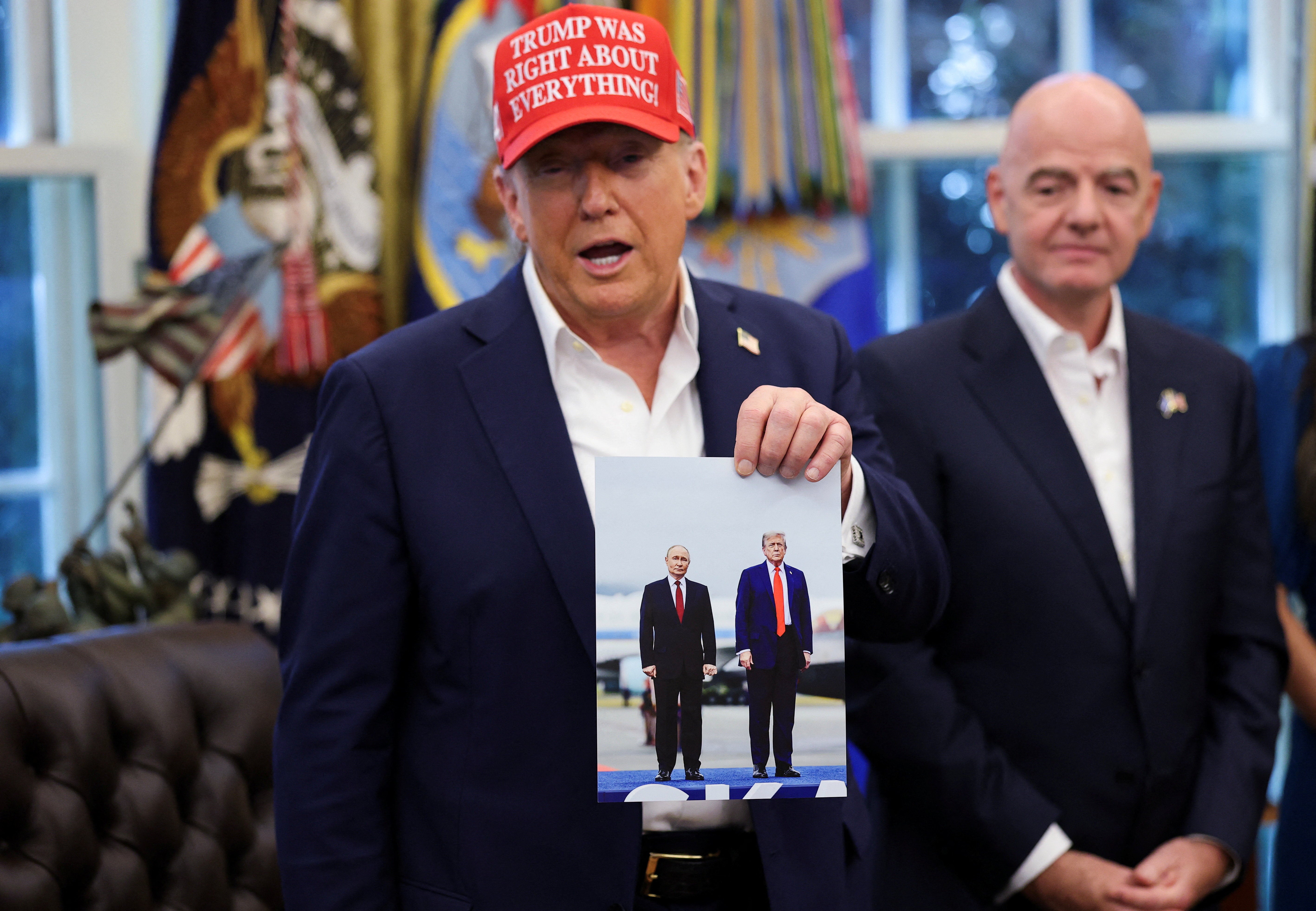 President Donald Trump holds an image of him and Russian president Vladimir Putin from their meeting in Alaska, as Fifa president Gianni Infantino stands