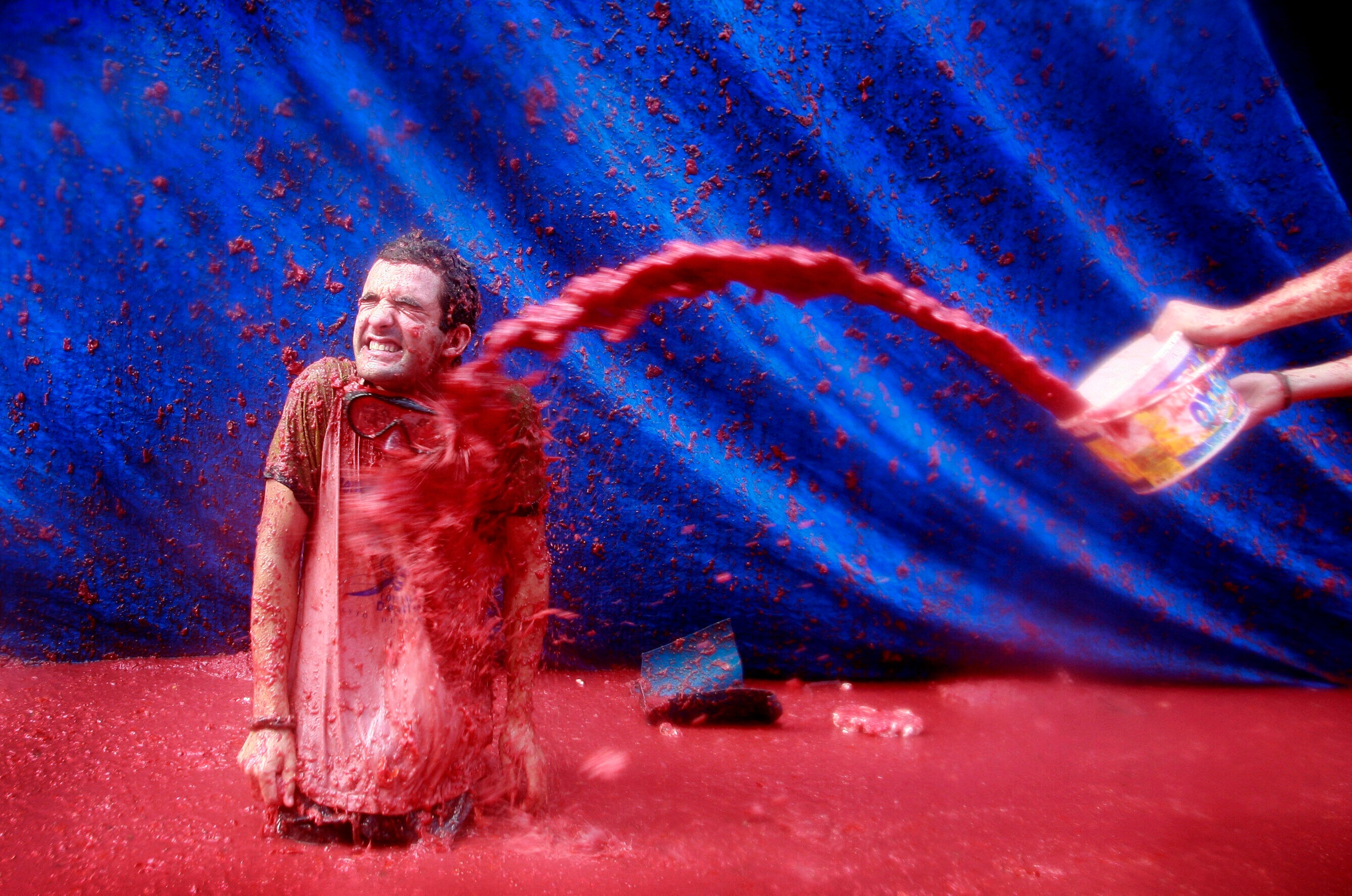 <p>A reveller throws tomato pulp at another during Tomatina, in Bunol</p>