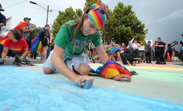 <p>A demonstrator uses blue chalk to color the street during a protest at a crosswalk that was repainted by the Florida Department of Transportation </p>