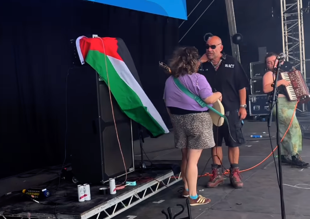 <p>A man appears to confront a member of The Mary Wallopers after she placed a Palestine flag over the band's amp during their set at Victorious Festval</p>