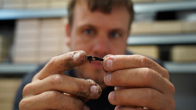 <p>Underwater archaeologist Peter Moe Astrup inspects a tiny animal bone, unearthed at an 8,500-year-old Stone Age coastal settlement submerged by sea level rise in Bay of Aarhus in Denmark</p>