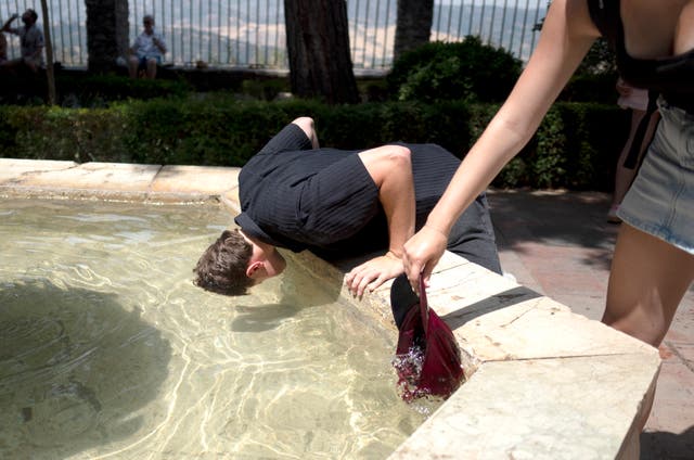 <p>Tourists cool off in a fountain during a heatwave in Ronda</p>