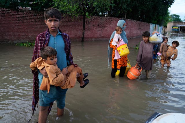 <p>A family walk toward a rescue boat arriving to evacuate them from a flooded area in Dhoop Sarhi village in Kasur district, Pakistan</p>