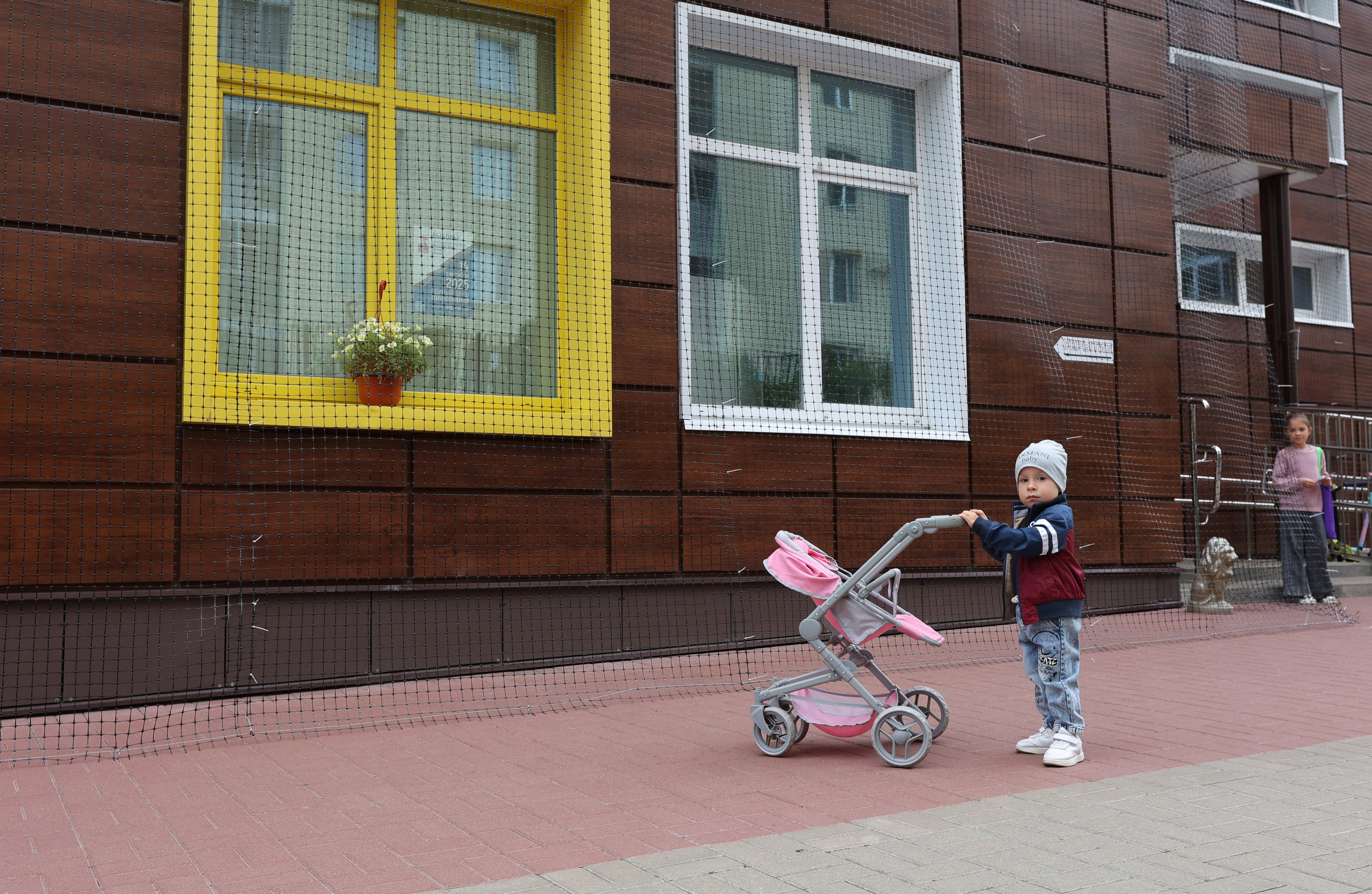 Children stand near a nursery, with netting installed