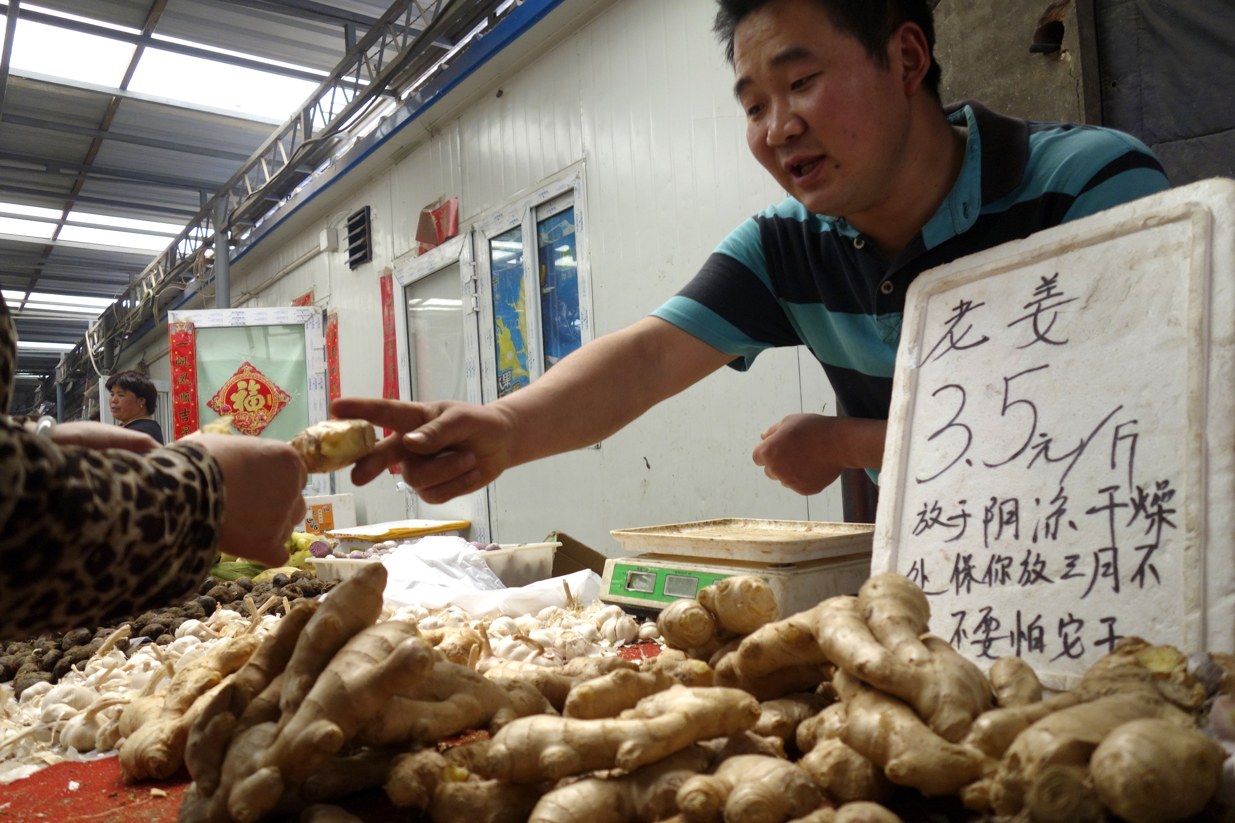 A Chinese seller sells ginger root in the Beijing market. Ginger is known to help settle intestine