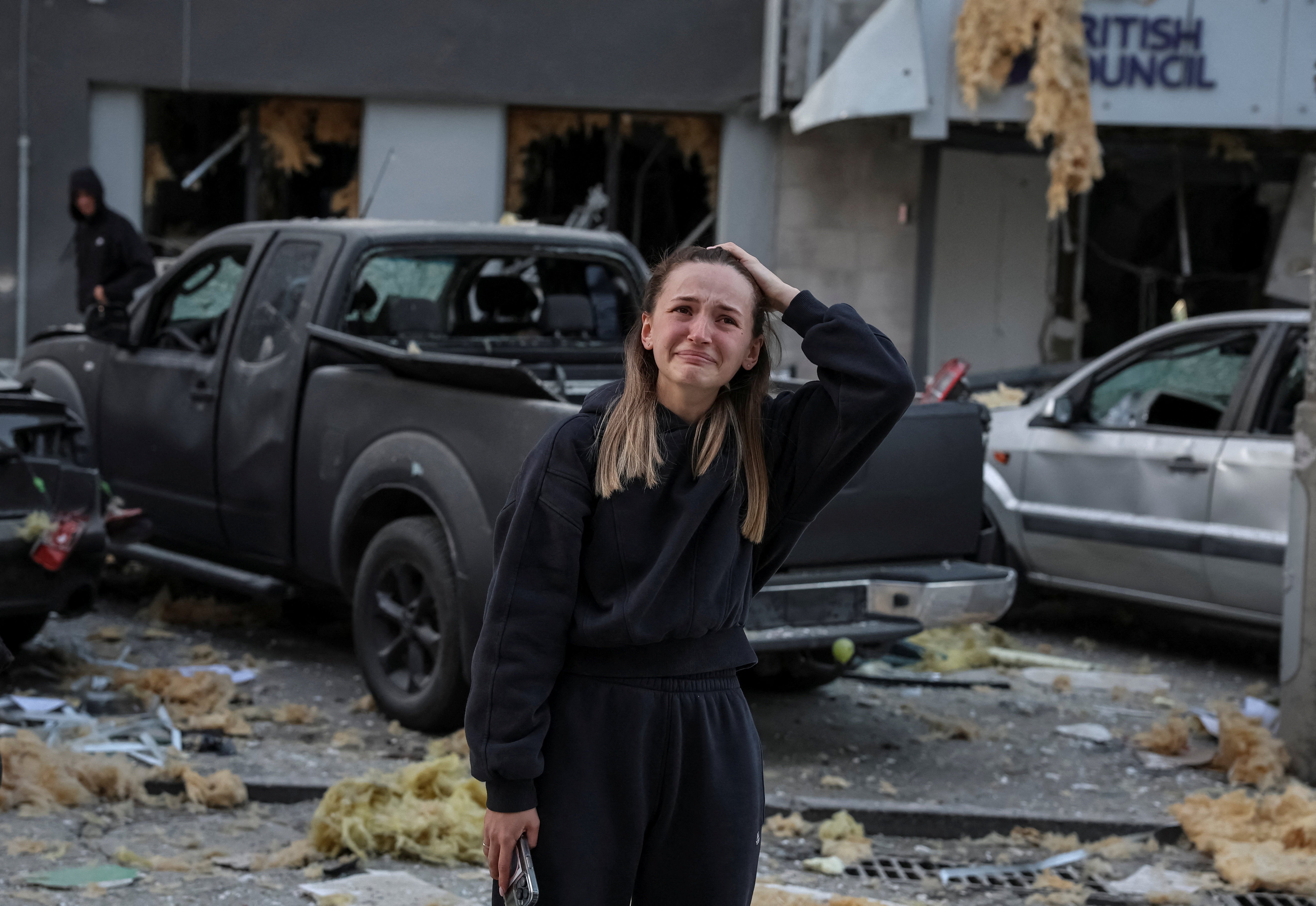 A woman reacts as she stands at the site of an apartment building