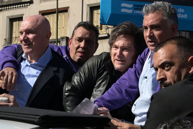 <p>Javier Milei reacts next to his party's candidate Jose Luis Espert, left, and security personnel as protesters throw objects at them in Lomas de Zamora</p>