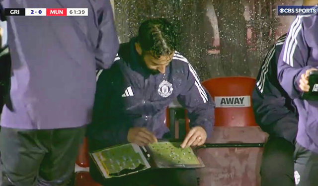 <p>Ruben Amorim consults his tactics board in the dugout during Man United's Carabao Cup second-round tie with Grimsby</p>