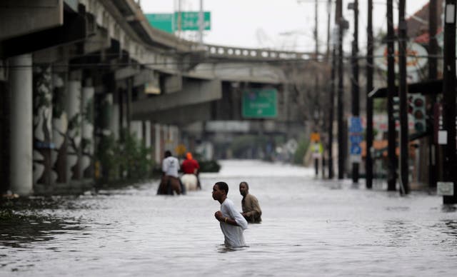 <p>New Orleans residents walk through chest deep floodwaters after Hurricane Katrina. It’s been 20 years since the storm hit the Louisiana coast</p>