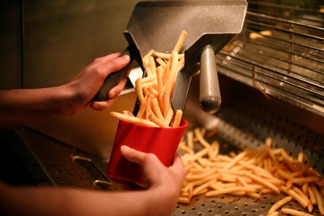 <p>An employee serves french fries in a reusable container at a McDonald's restaurant in Levallois-Perret, near Paris,</p>