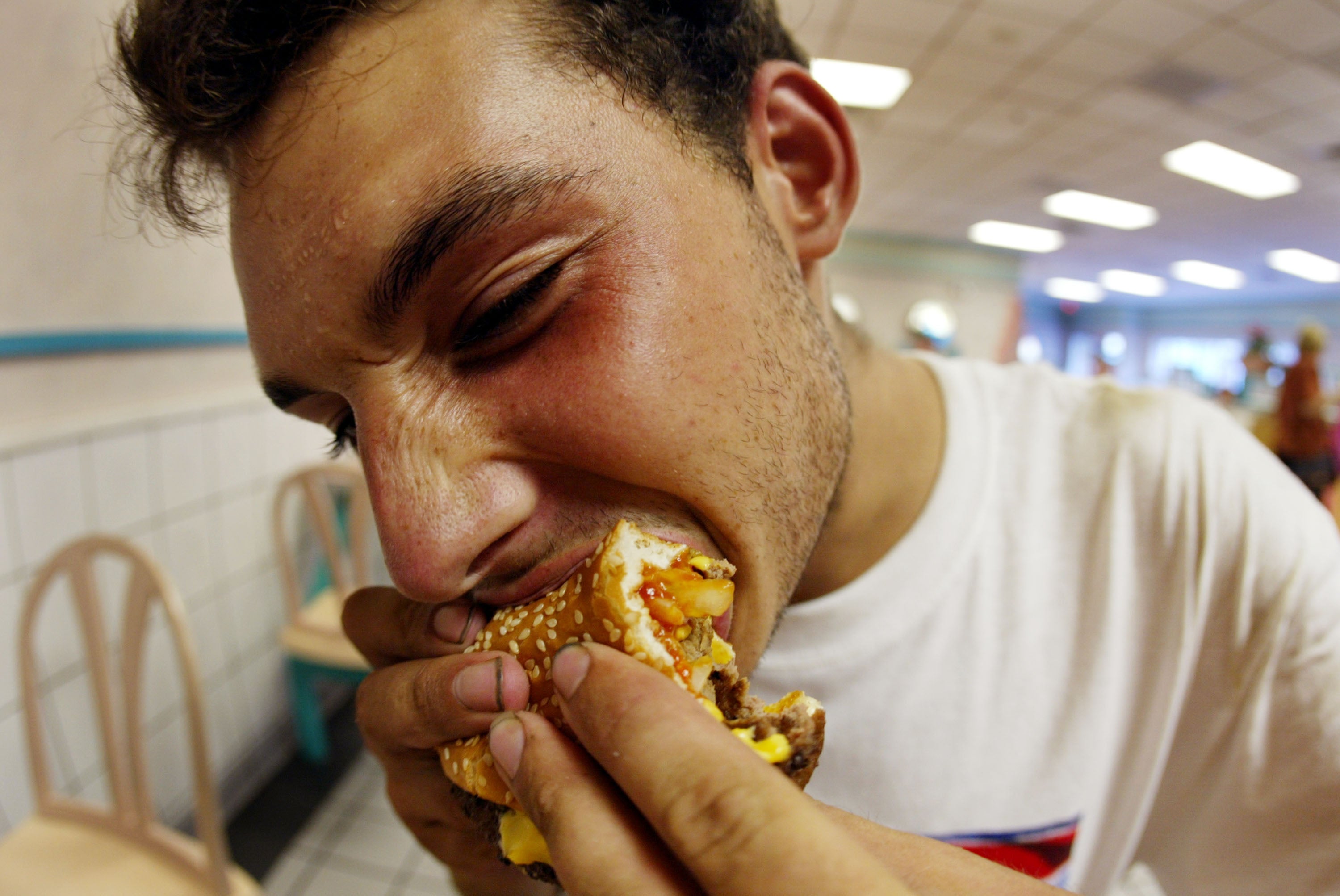 A man bites into a double cheeseburger. Eating ultra-processed foods can affect male reproductive health, researchers said this week