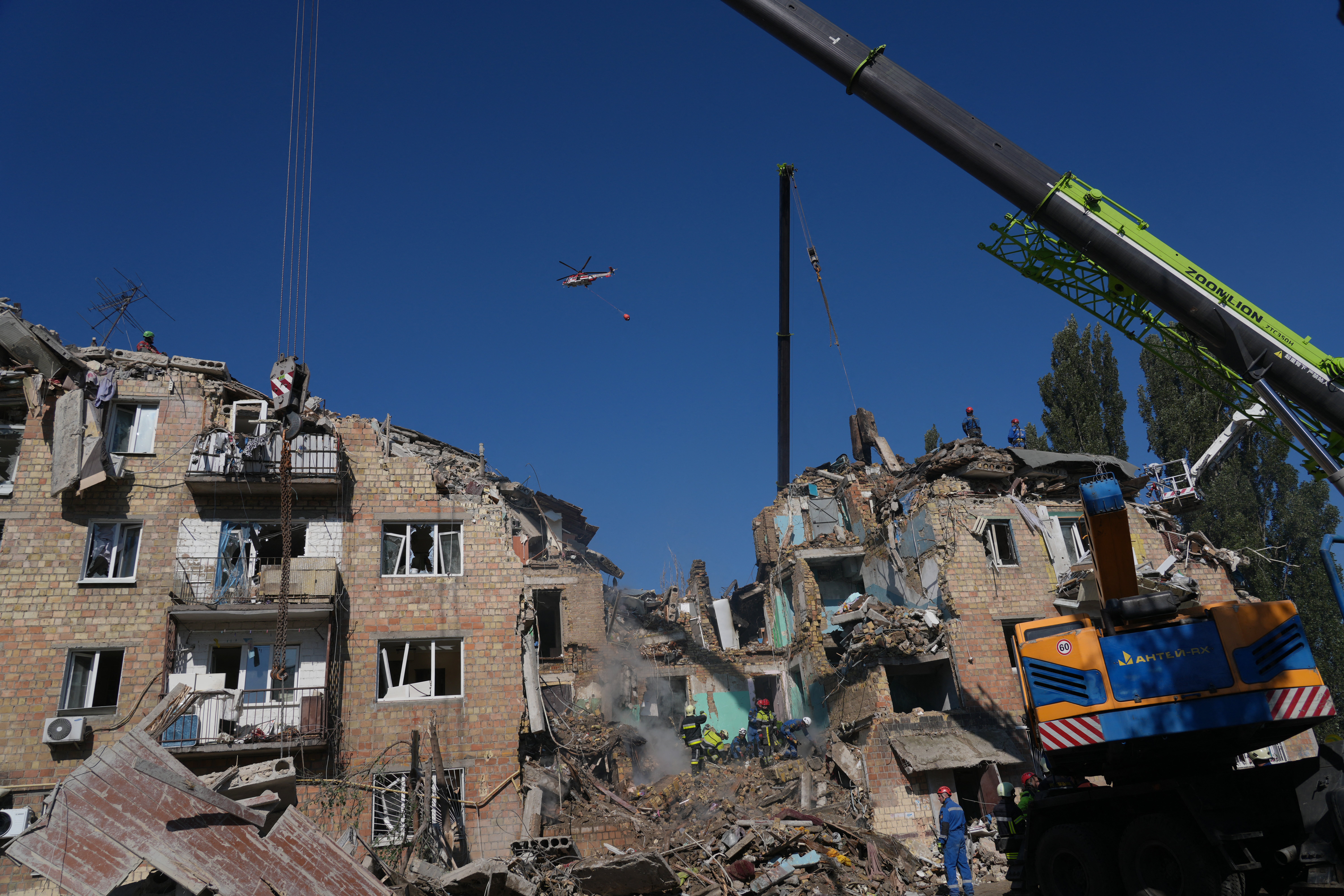 A firefighting helicopter flies over a heavily damaged residential building, following a large-scale Russian drone and missile attack on Kyiv