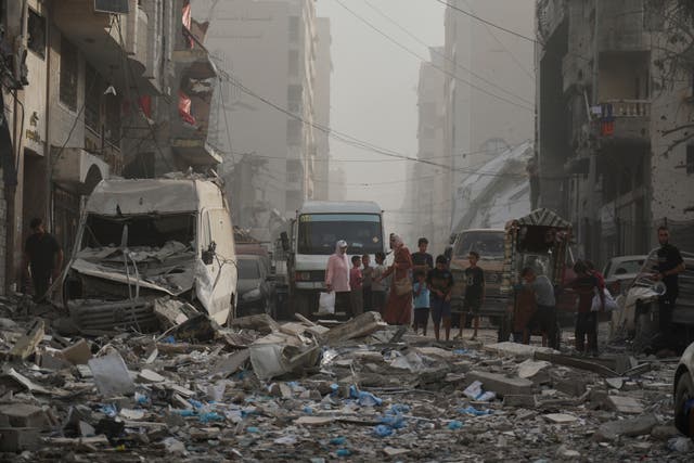 <p>Palestinians stand next to a heavily damaged building in the Rimal neighborhood of Gaza City on Sunday August 31 2025</p>