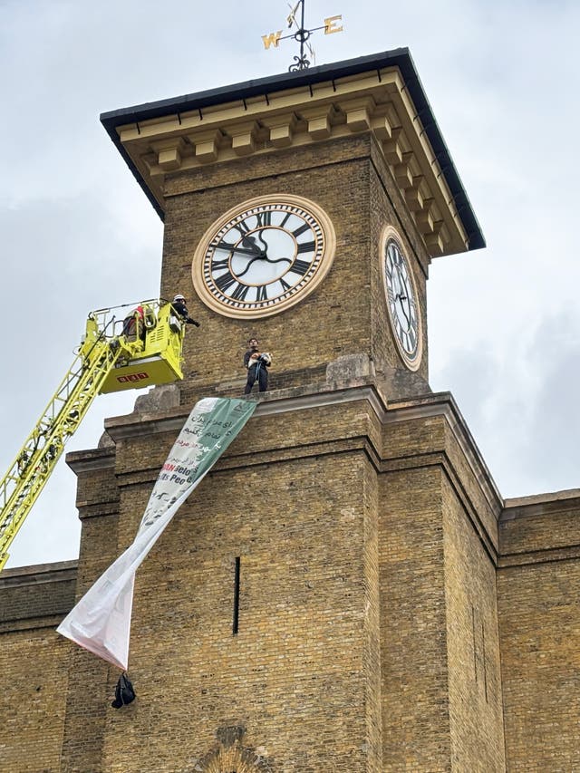 <p>A London Fire Brigade cherry picker has been raised to a protester standing on a ledge in front of the King's Cross clock tower in London</p>