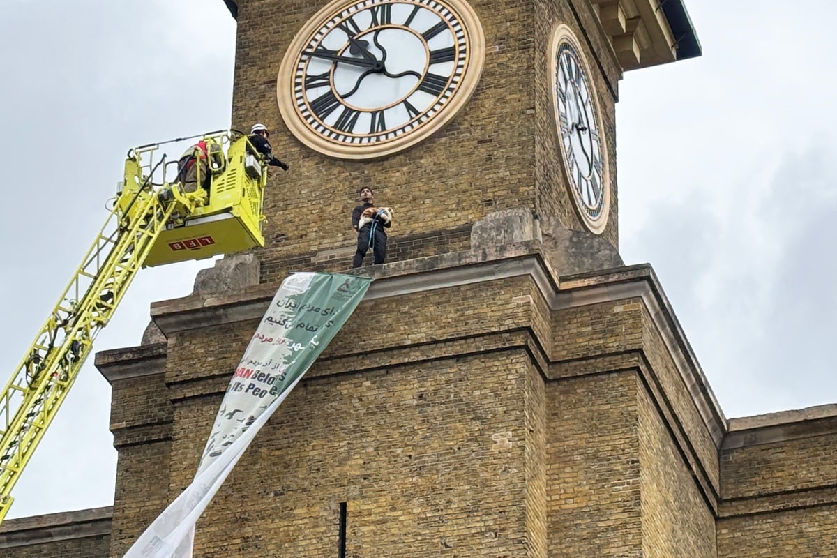 Protester carrying dog scales clock tower at London train station