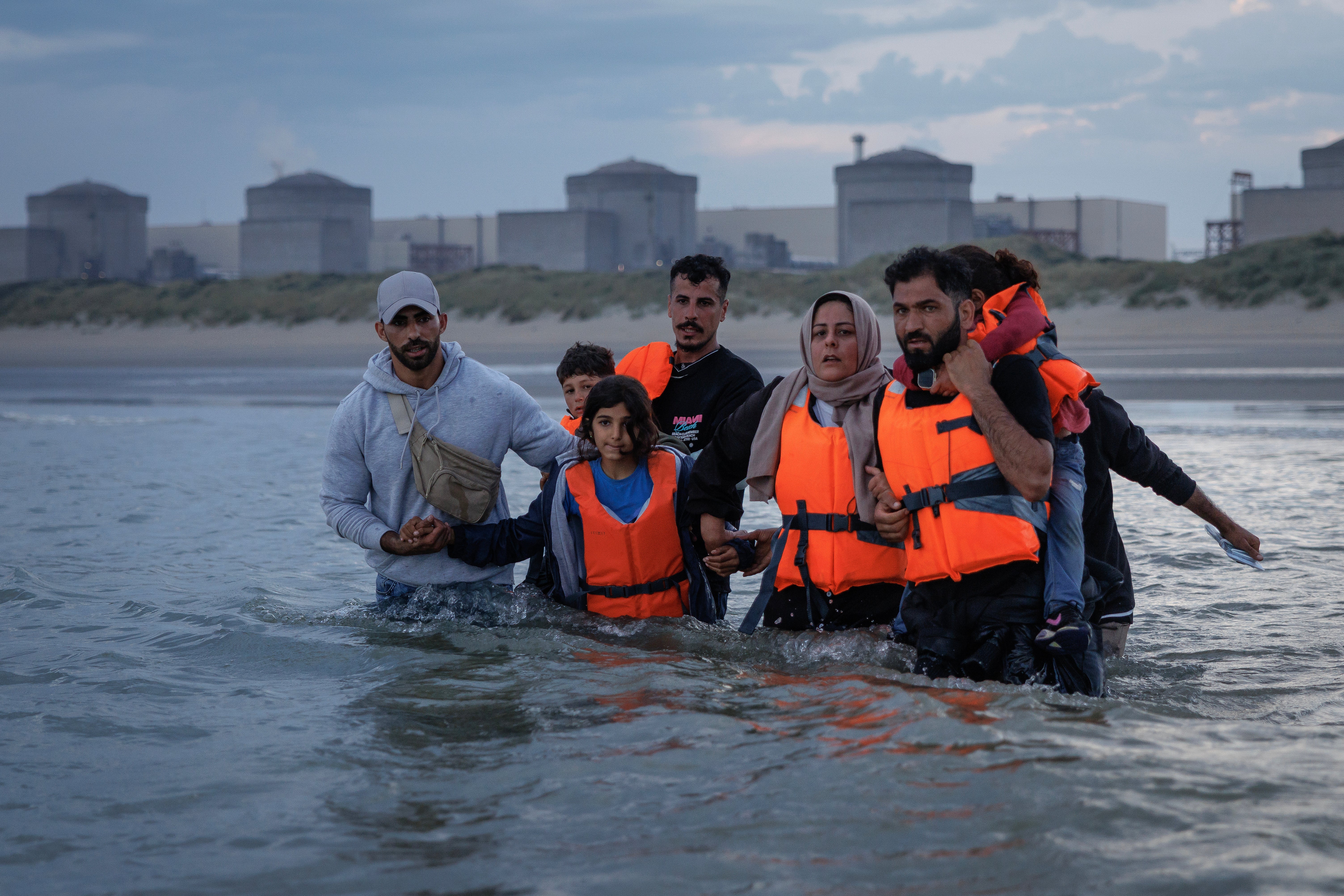 Migrant families wade into the sea off the coast of northern France in an attempt to board a small boat to cross the English Channel