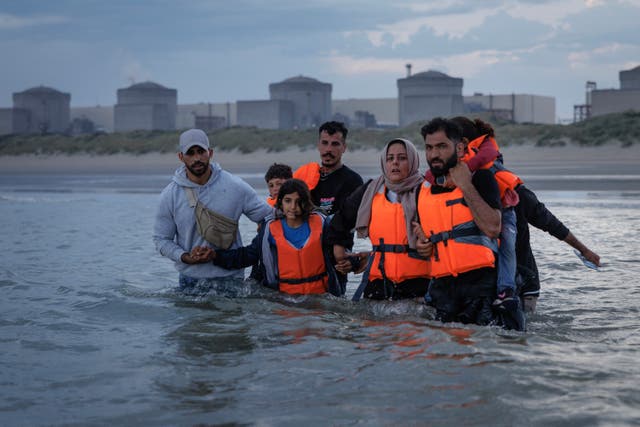 <p>Migrant families wade into the sea off the coast of northern France in an attempt to board a small boat to cross the English Channel</p>