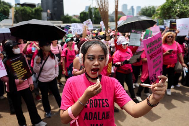 <p>Protestors are brandishing brooms as a symbol of their calls for reform, outside the Indonesian parliament building in Jakarta, Indonesia</p>