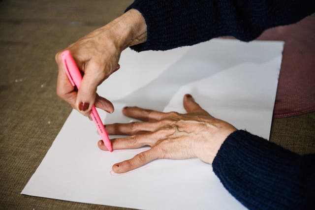 <p>Alzheimer's patient draws around her hand as part of an activity </p>