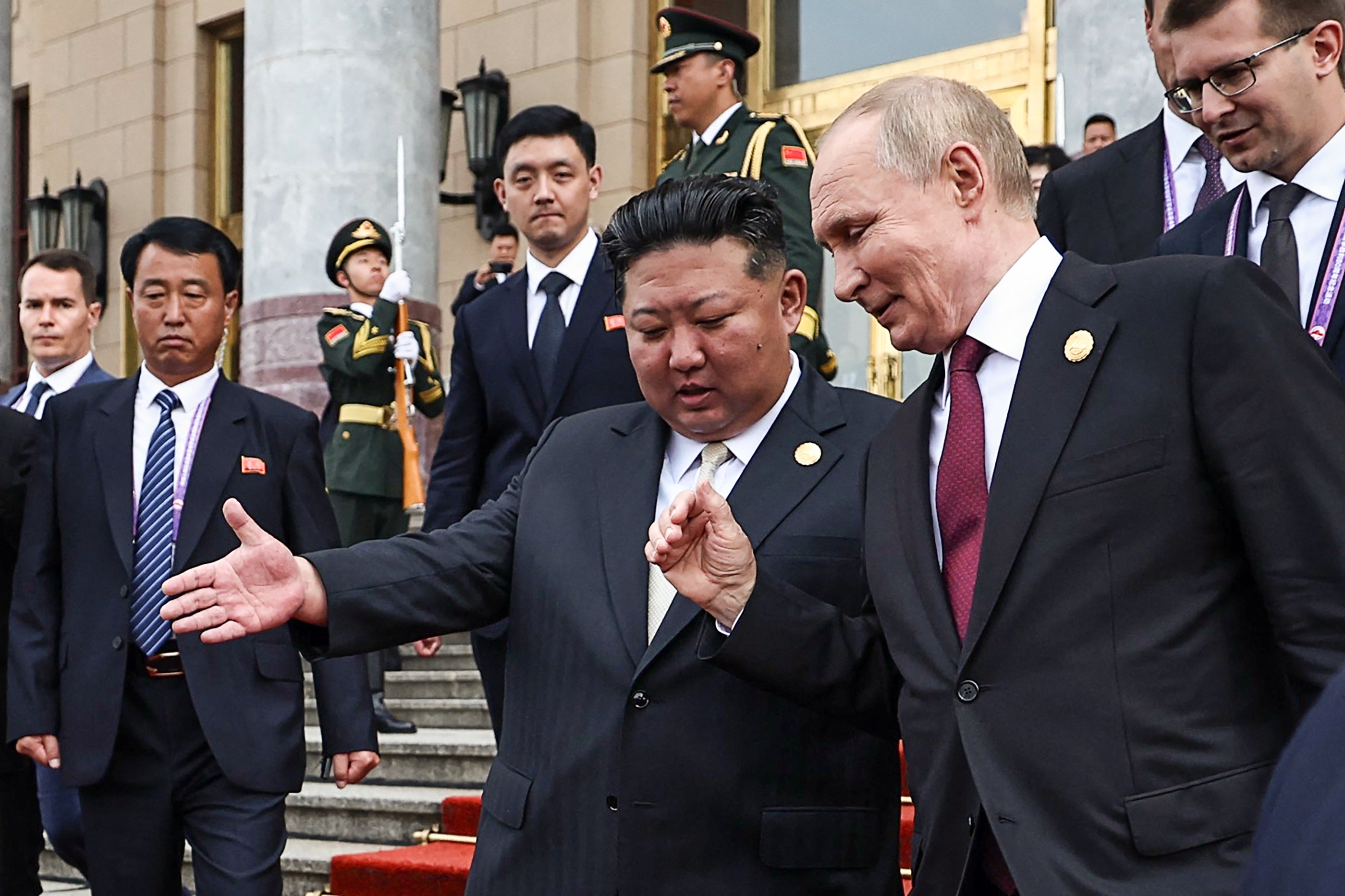 Russia's President Vladimir Putin (R) and North Korea's leader Kim Jong Un (C) leave after their meeting in Beijing